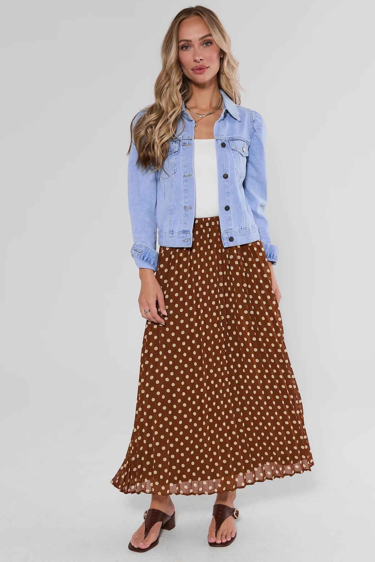 Brown polka dot maxi skirt styled with light blue denim jacket, white top, and brown sandals - Styled Look | Avara