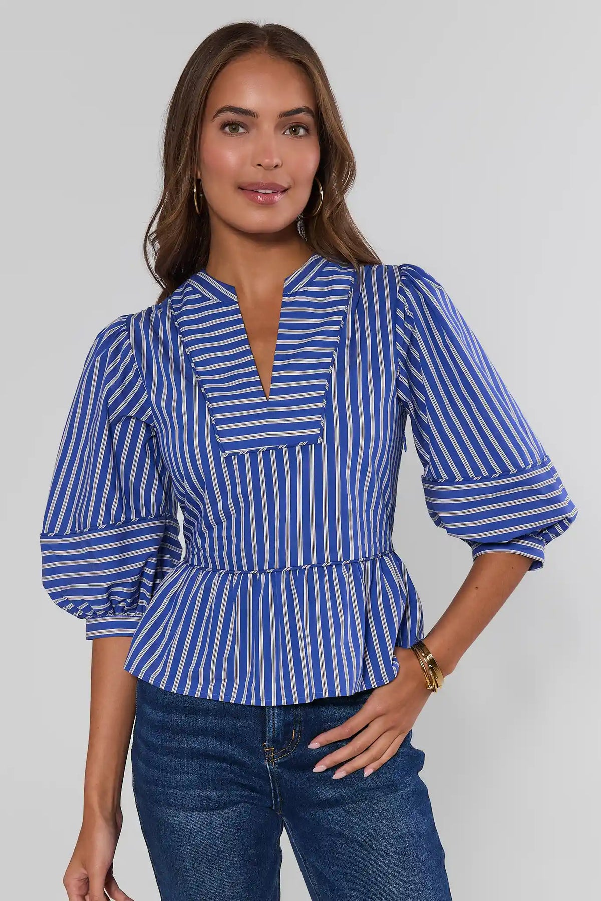 Blue striped split neck peplum top with puff sleeves, front view, paired with dark jeans | Avara