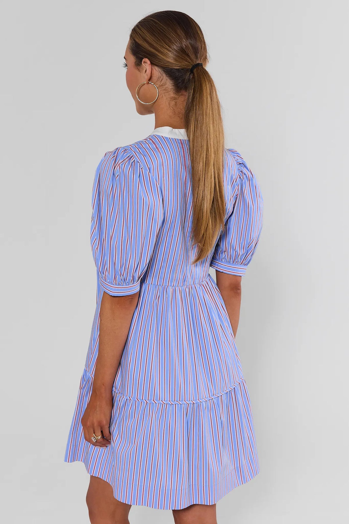 Back view of blue and red striped puff-sleeve tiered short dress with white contrast collar | Avara
