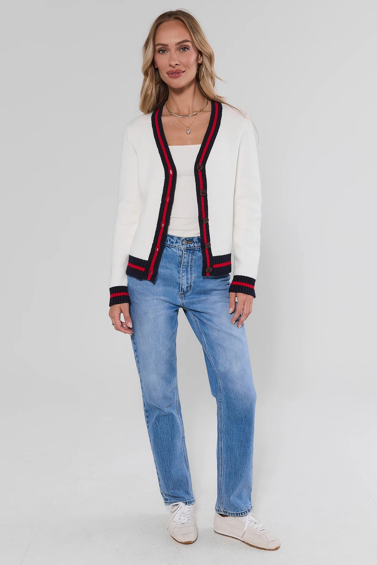 White knit cardigan with navy red striped trim, styled with light blue jeans and white sneakers - Full Length | Avara