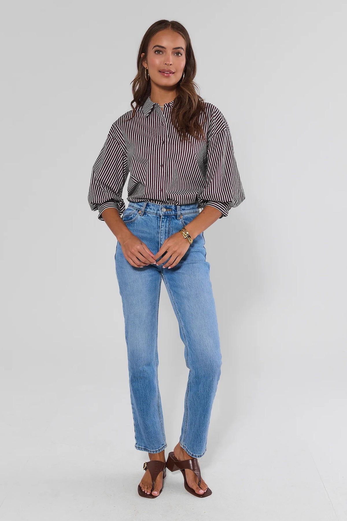 Burgundy striped button-up top styled with light-wash jeans and brown heeled sandals, full-length on model | Avara