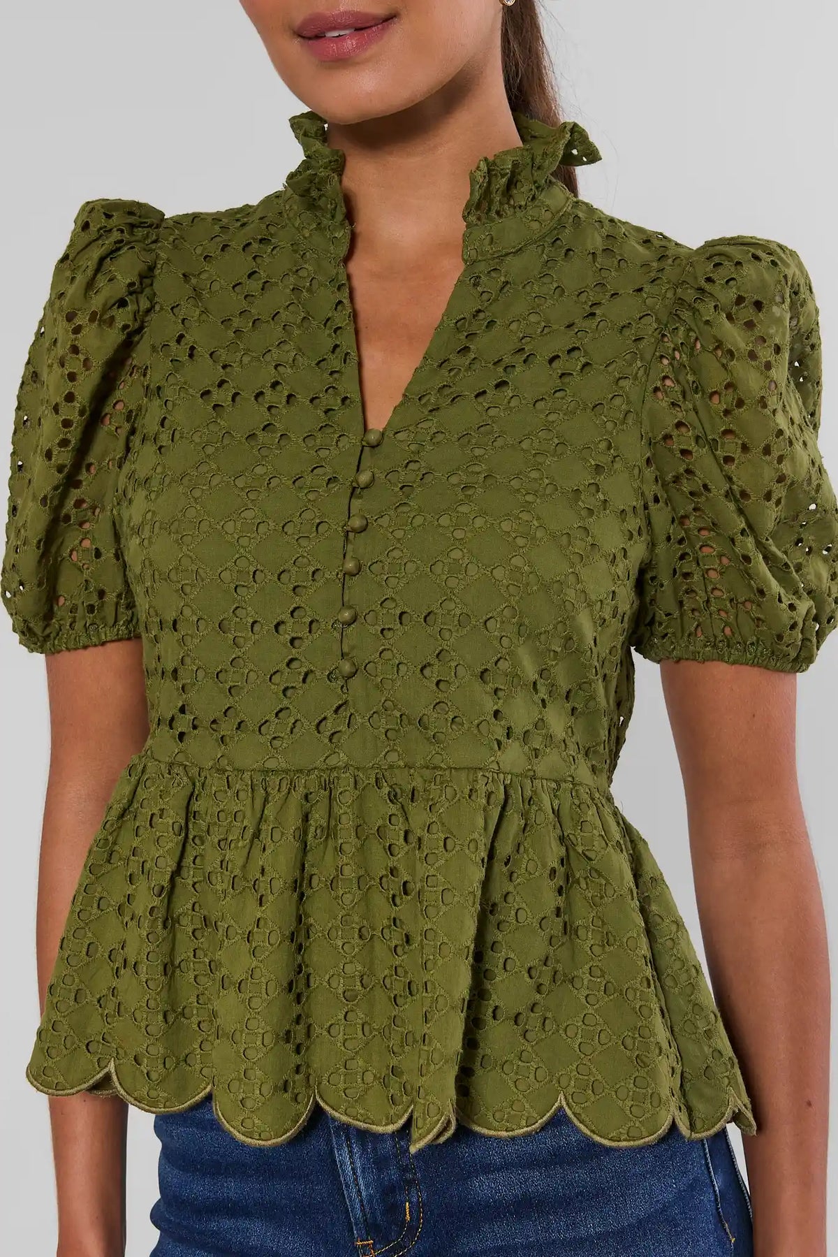 Olive green eyelet peplum top with puff sleeves, button placket, and scalloped hem - Close-Up Detail | Avara