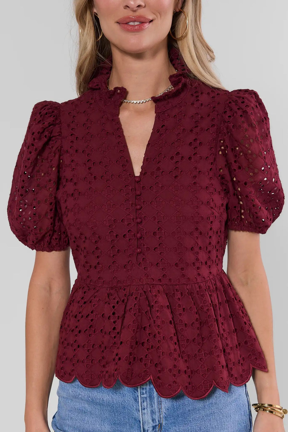 Maroon eyelet peplum top with split neckline, puff sleeves, and scalloped hem - Close-Up Detail | Avara