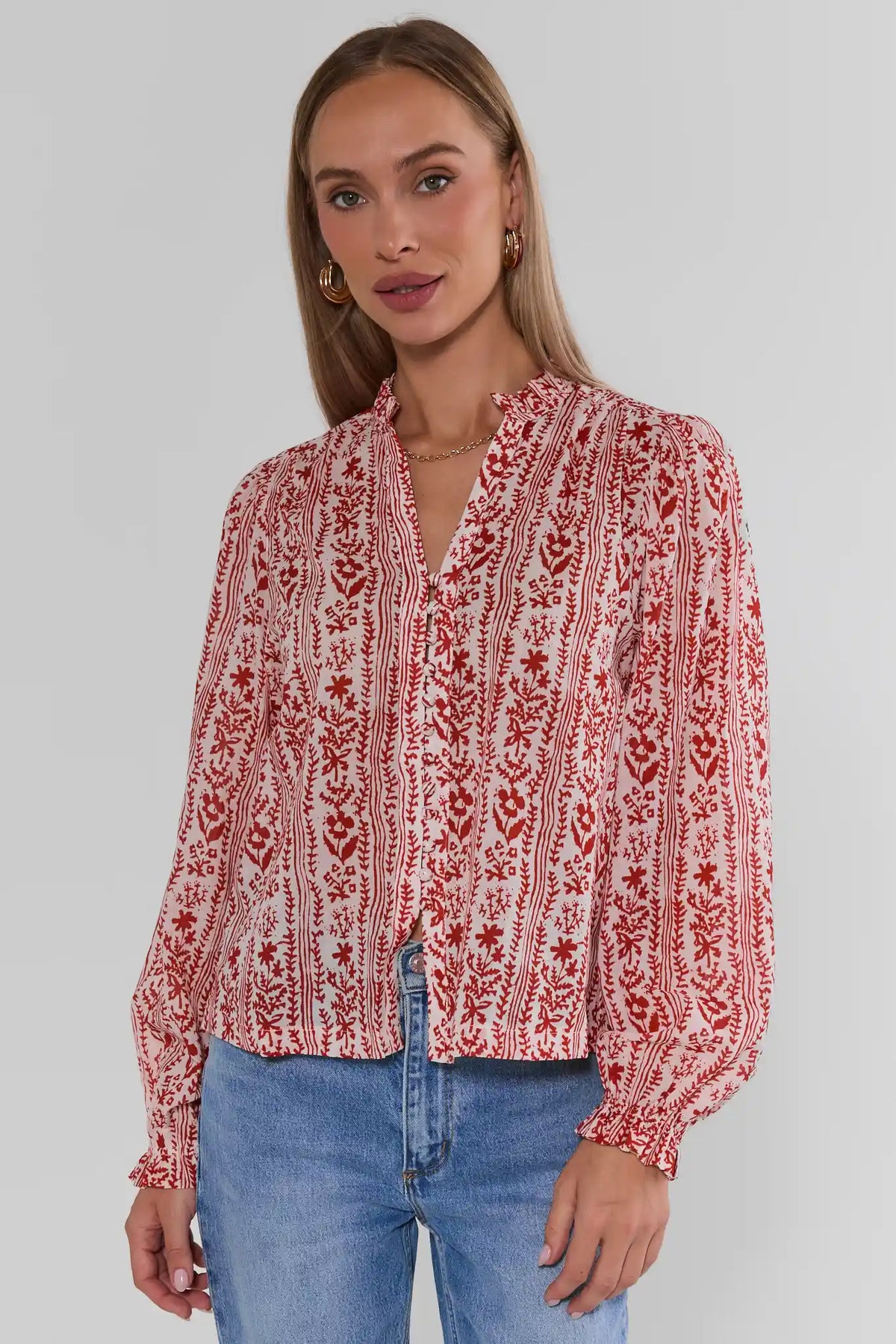 Woman wearing Red Floral Printed Button Up Top with long sleeves and ruffle cuffs, styled with blue jeans - Side View | Avara