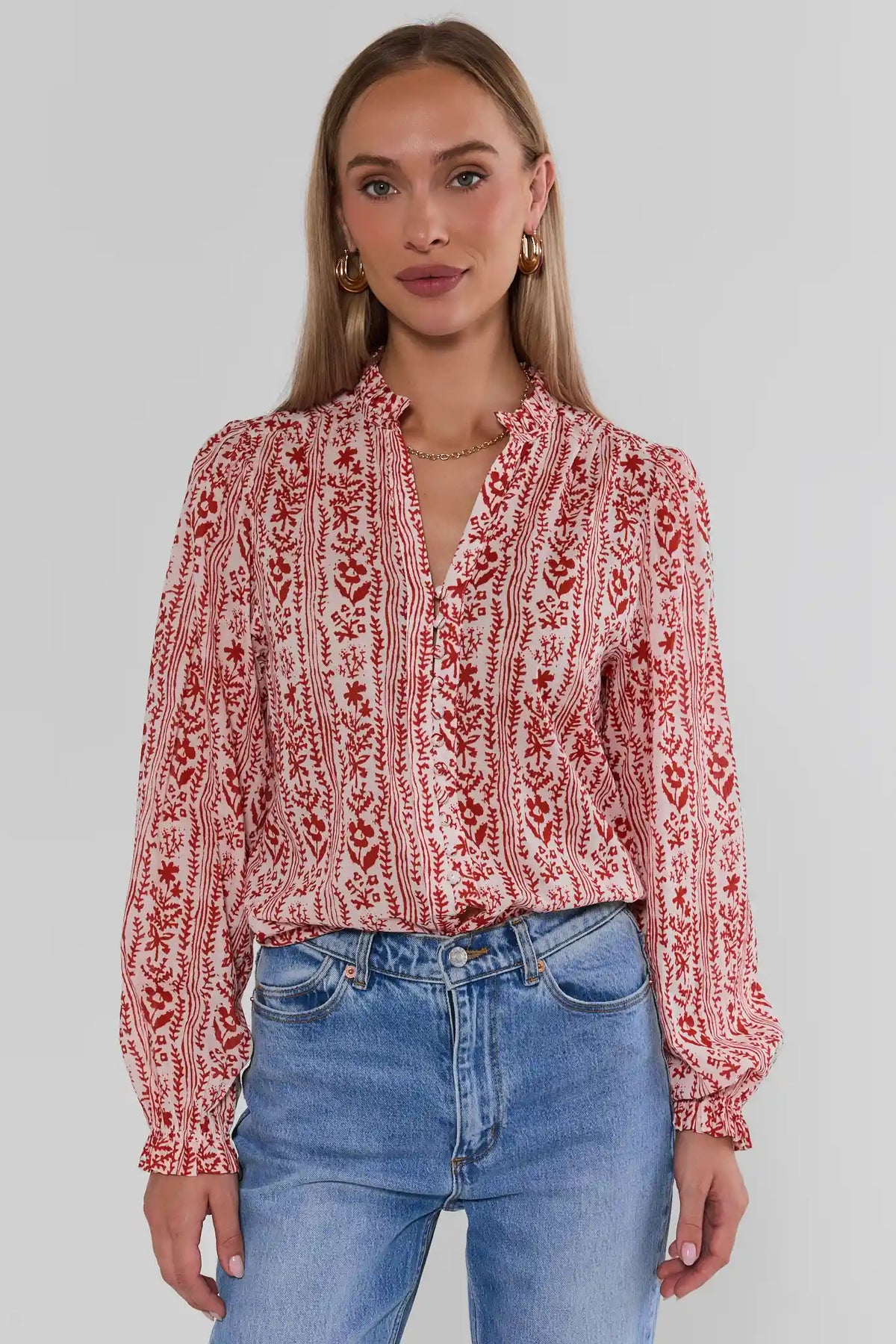 Woman wearing Red Floral Printed Button Up Top with ruffle neckline, styled with blue jeans - Front View | Avara