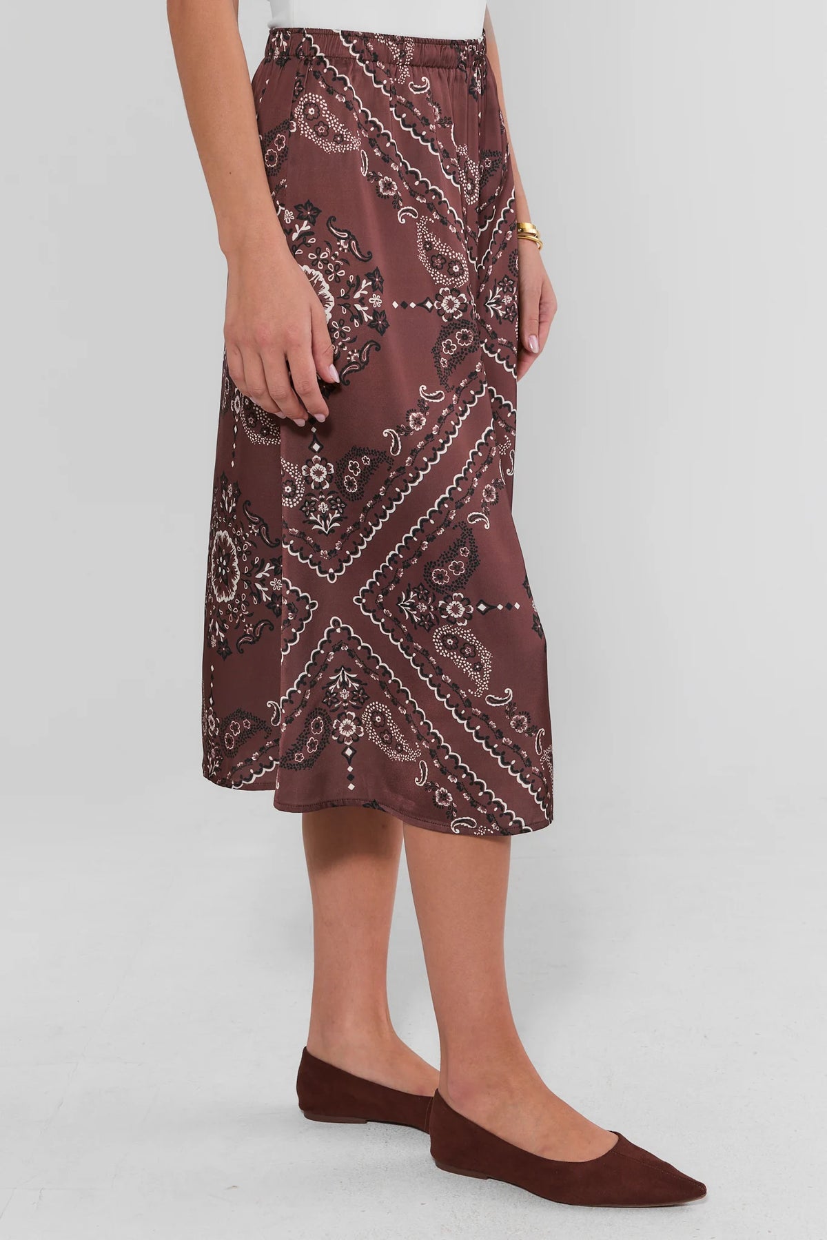 Brown bandana midi skirt with allover paisley print, elastic waistband, and flowy A-line hem - Side View On Model | Avara
