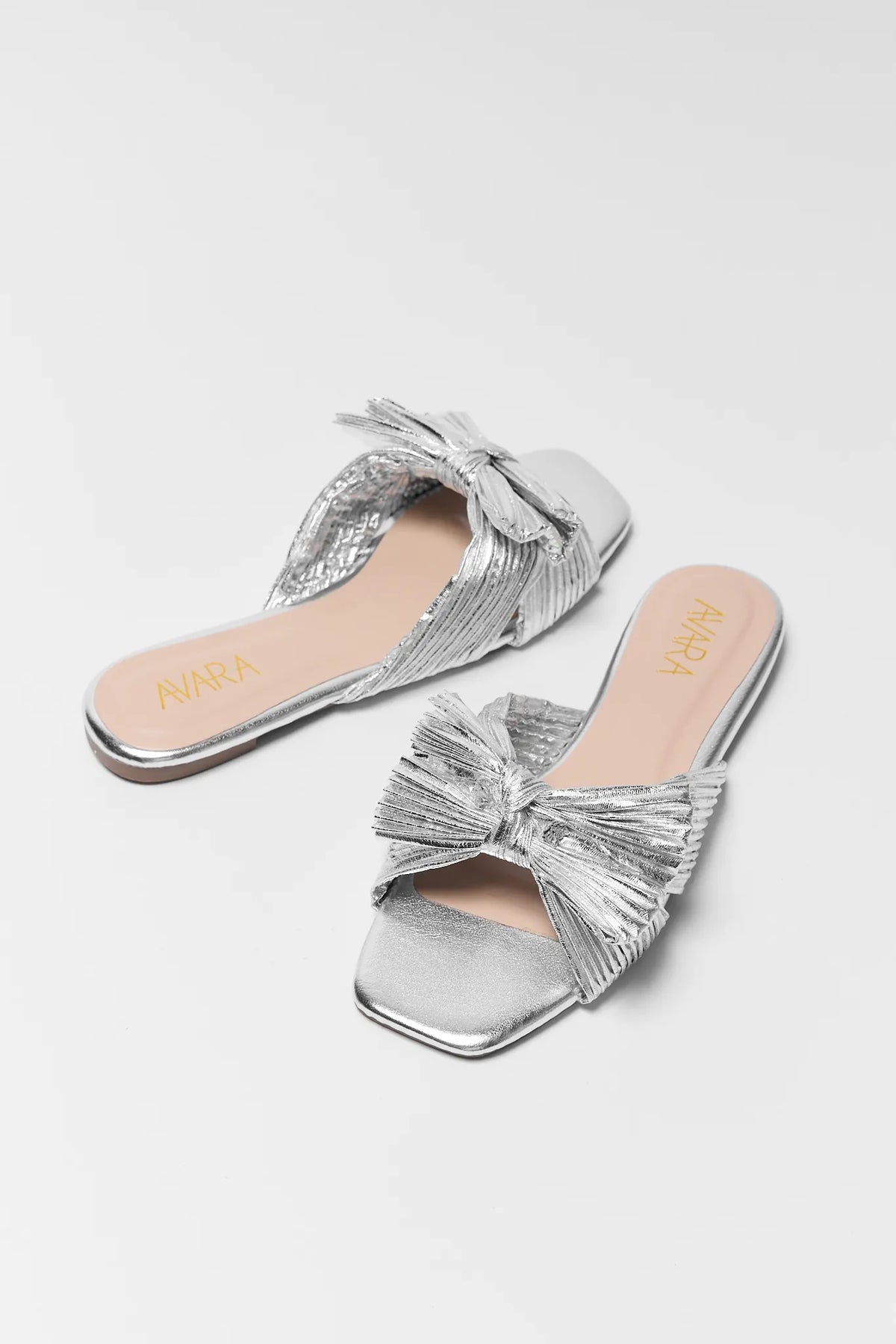 Silver metallic knot sandals with pleated bow detail, pair overhead view | Avara