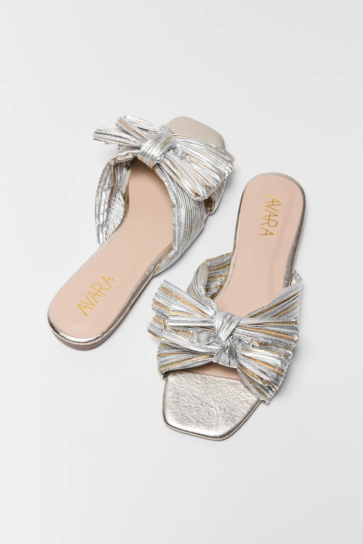 Silver and gold two tone metallic knot sandals, pair overhead view on gray background | Avara