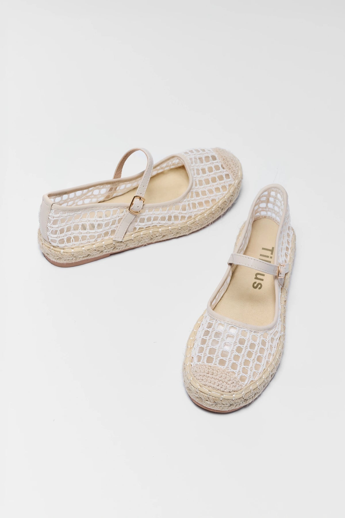 Pair of white woven shoes with straps on a light gray background