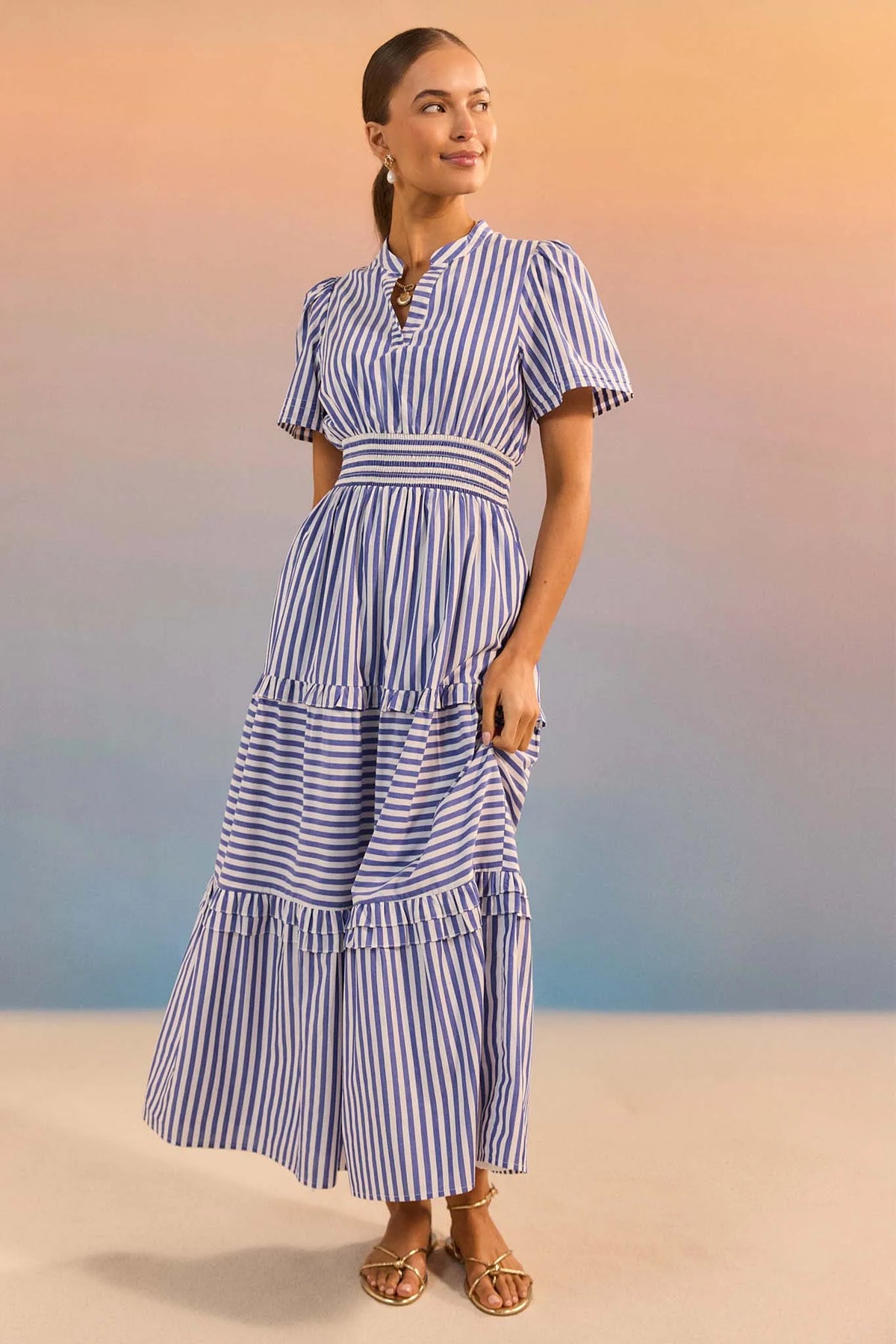 Woman wearing a blue and white striped dress against a blurred natural background