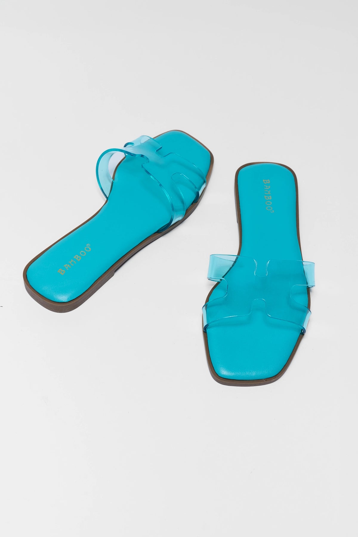 Turquoise blue jelly slip-on sandals pair, angled flat lay showing footbed and H-strap detail | Avara