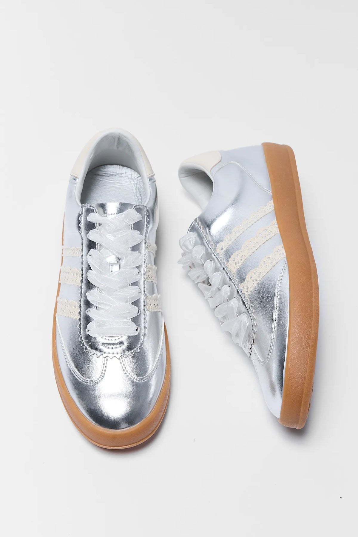 silver sneakers with lace details and ribbon on white background