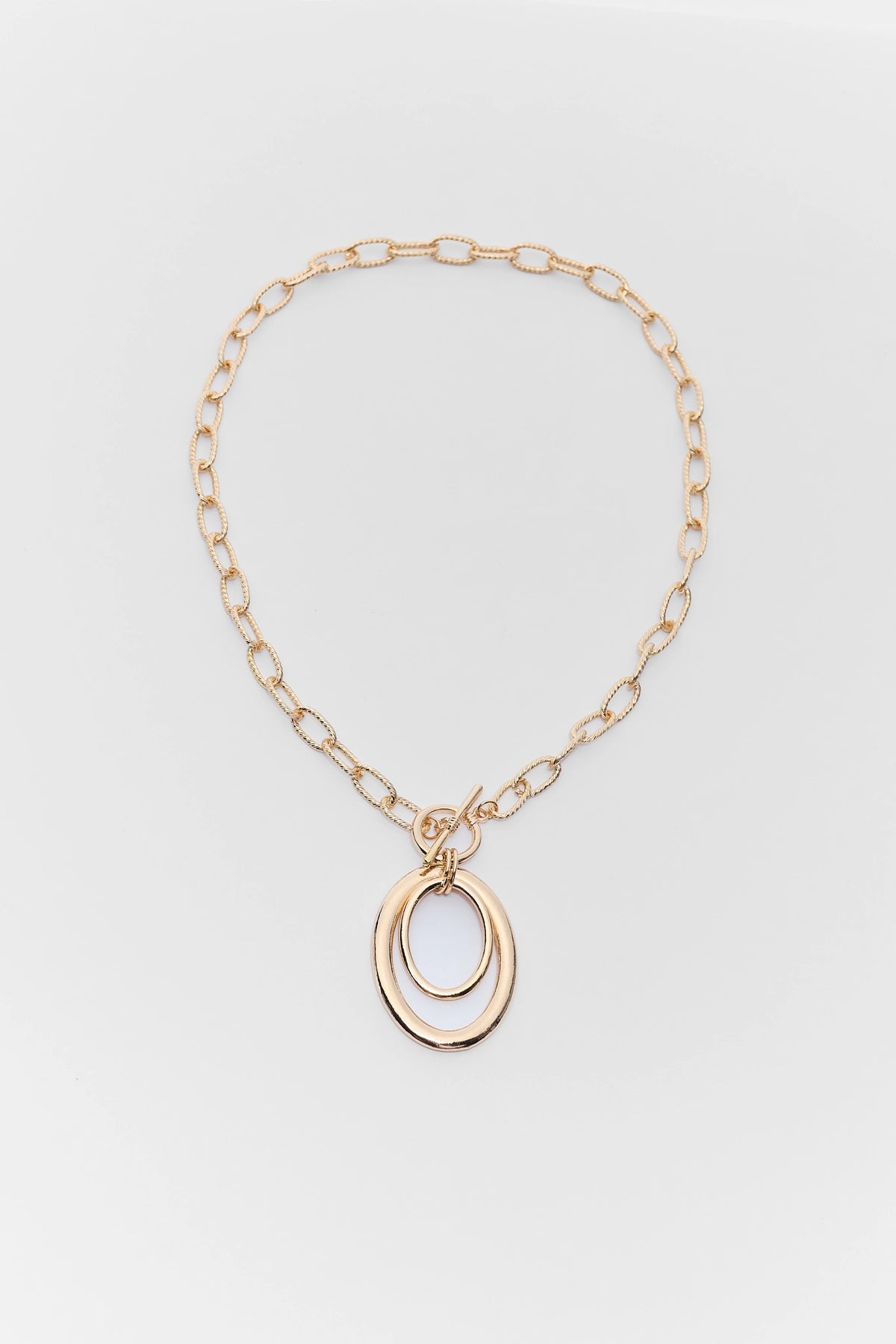 Gold chain necklace with a pendant on a light gray background