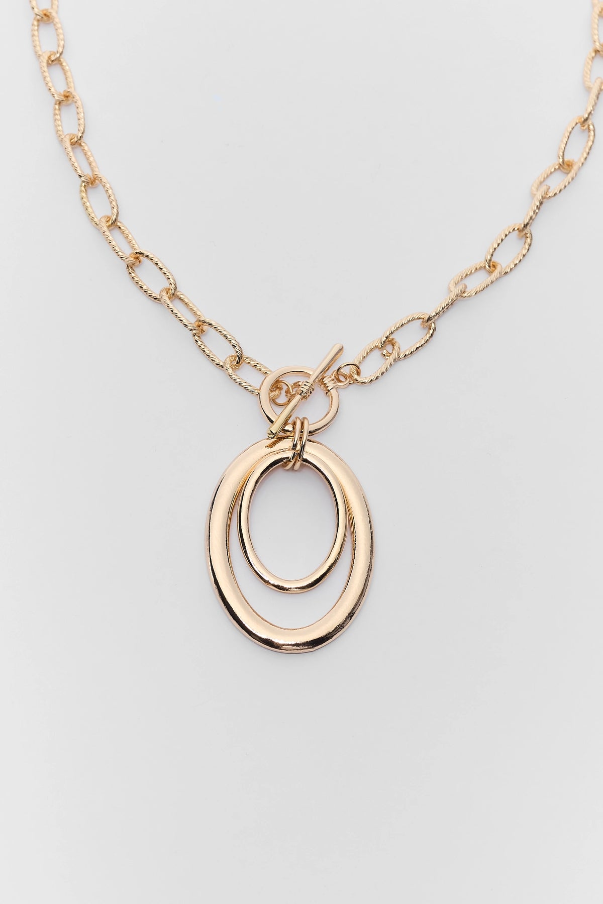 close up Gold necklace with a double oval pendant on a light gray background