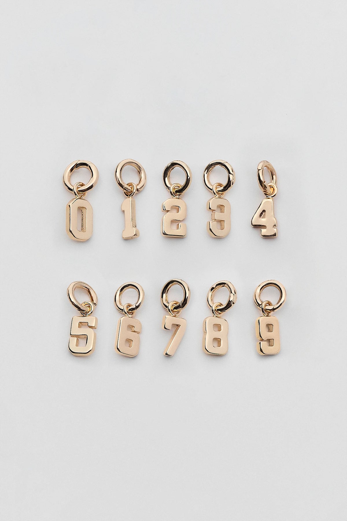 Gold game day number charms 0–9 polished finish flat lay, game day necklace bracelet pendants | Avara