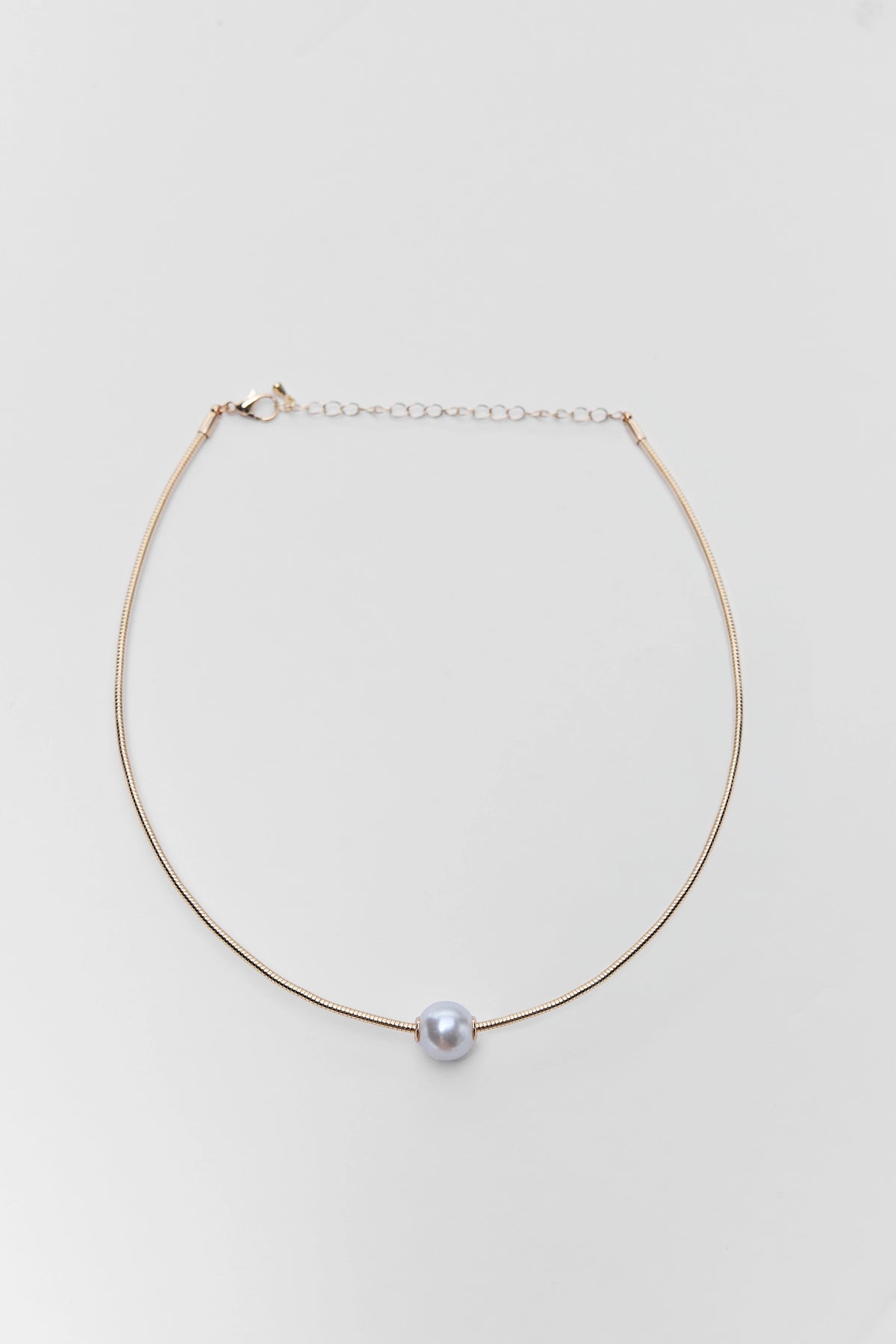Gold herringbone chain necklace with single pearl charm - Flat Lay | Avara