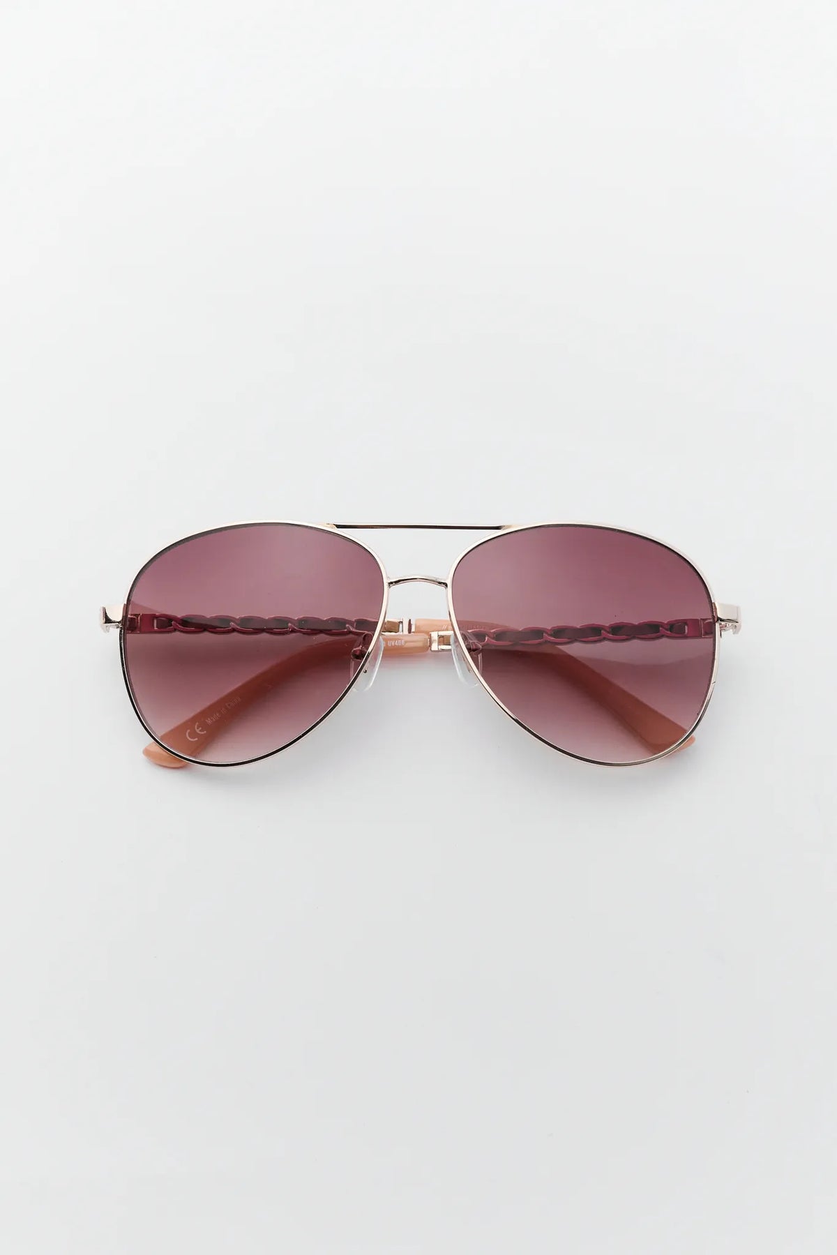 Aviator sunglasses with rose gold frame and gradient brown lenses, chain-detail arms - Flat Lay | Avara