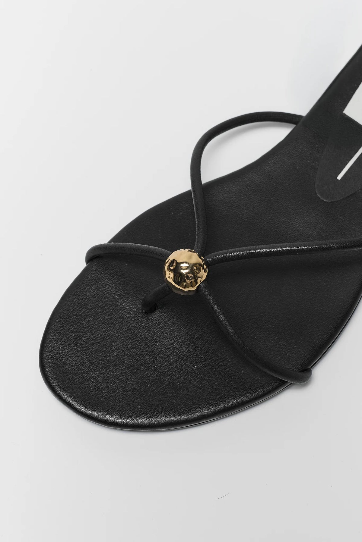 Close-up of black Kenley sandal toe strap with hammered gold ball embellishment - Detail View | Avara