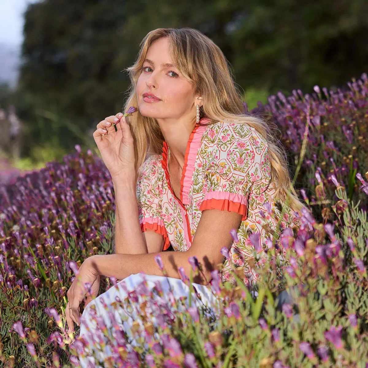 Woman sitting in a field of lavender wearing a floral dress.