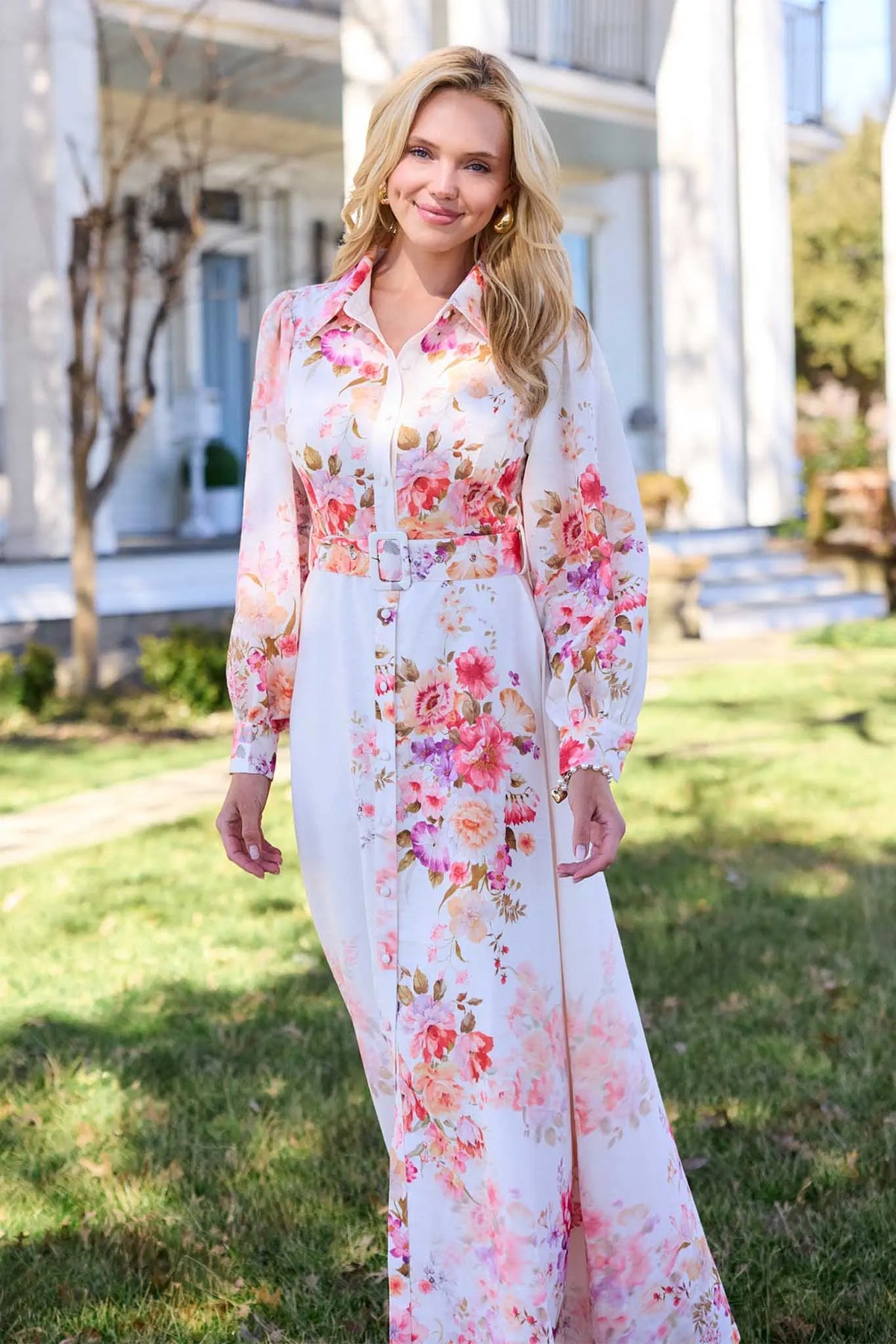 Woman wearing a floral dress standing outdoors with a house in the background