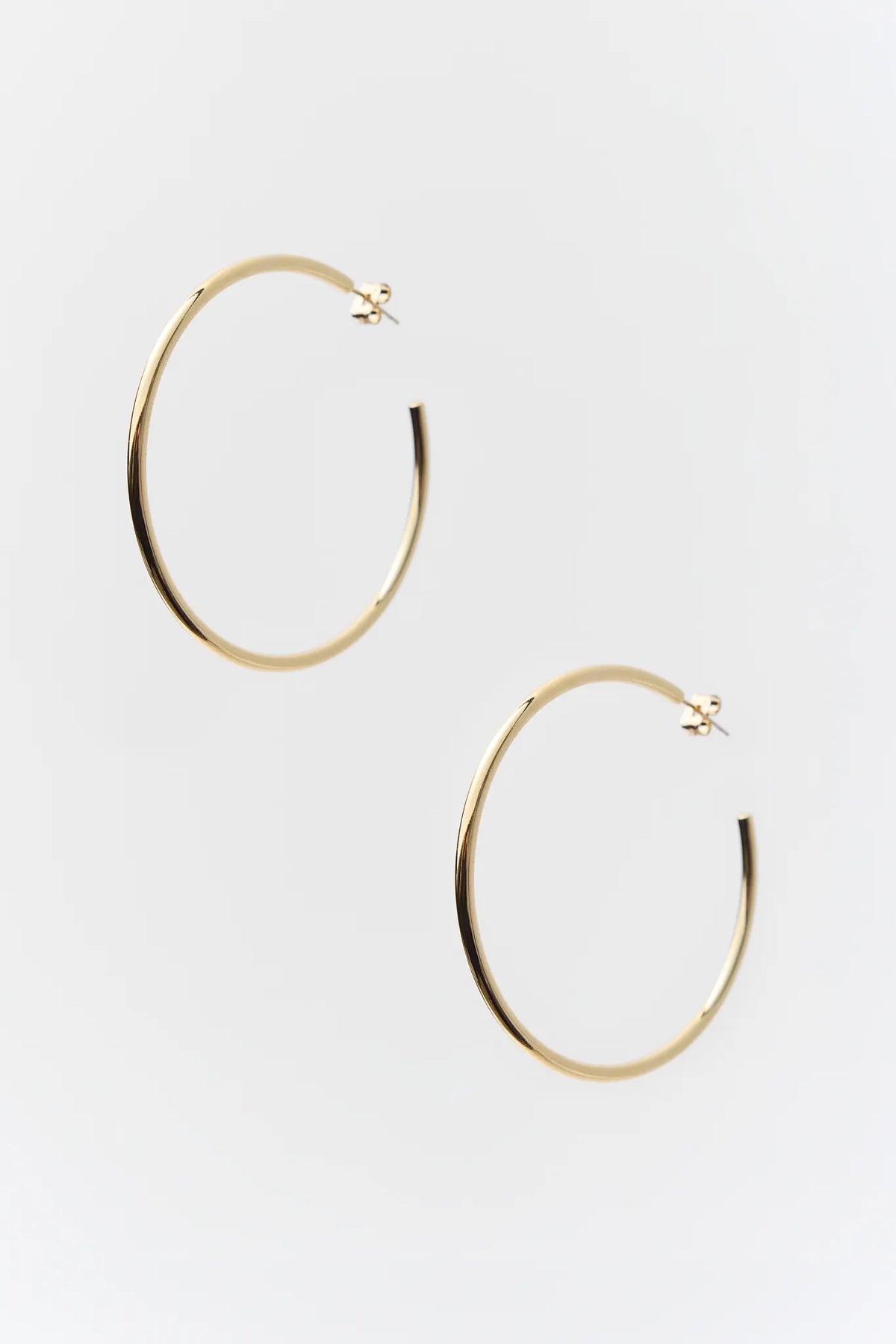 Leigh Gold Hoop Earrings 2 Diameter with a thin, gold-colored hoop design, featuring a 14k gold-dipped finish and push backs for pierced ears.