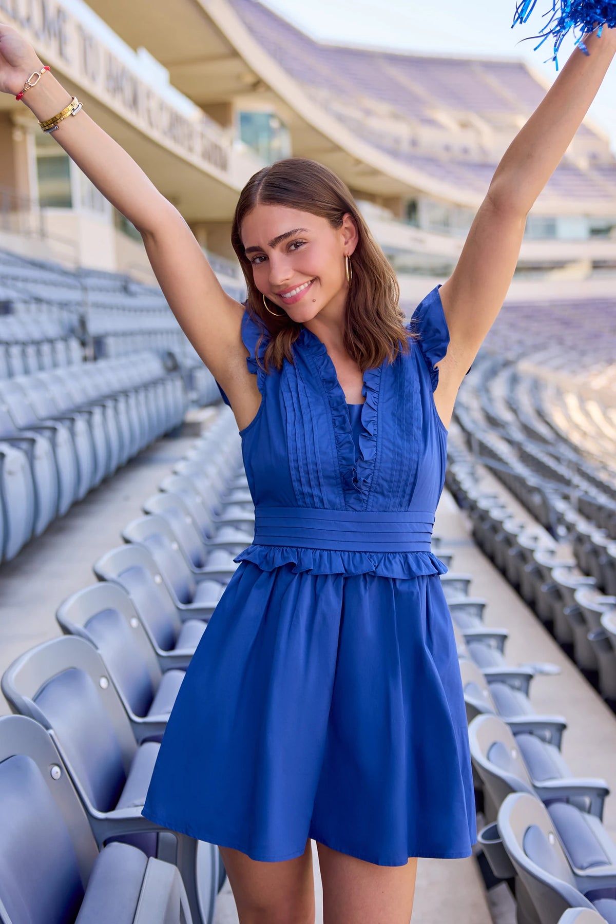 Makayla Blue Flutter Sleeve Short Dress on model with arms raised at stadium, royal blue a-line game day dress | Avara