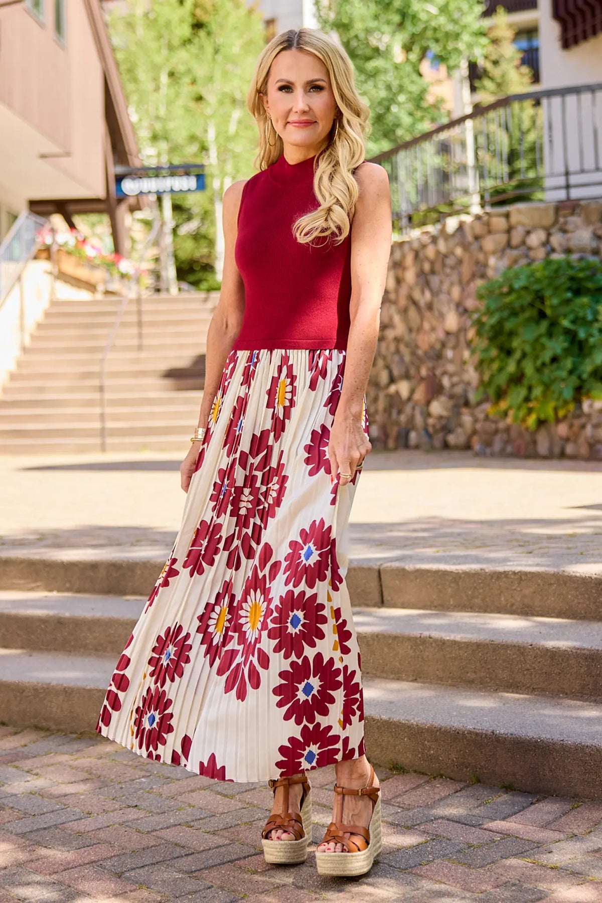 Woman wearing Marcia Burgundy Midi Dress outdoors on steps, floral pleated skirt, ribbed bodice | Avara