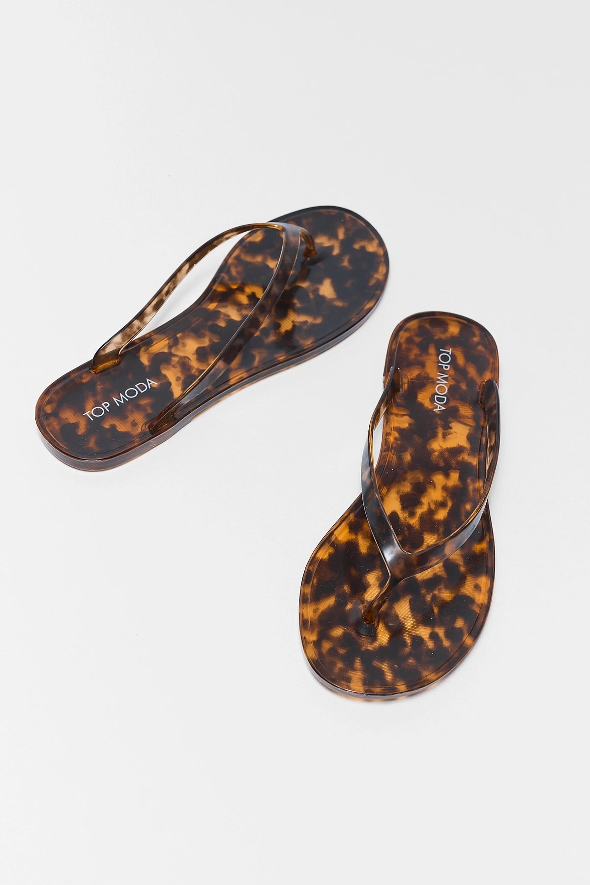 Marley Tortoise Jelly Sandals pair angled flat lay - glossy tortoiseshell flip flop silhouette | Avara