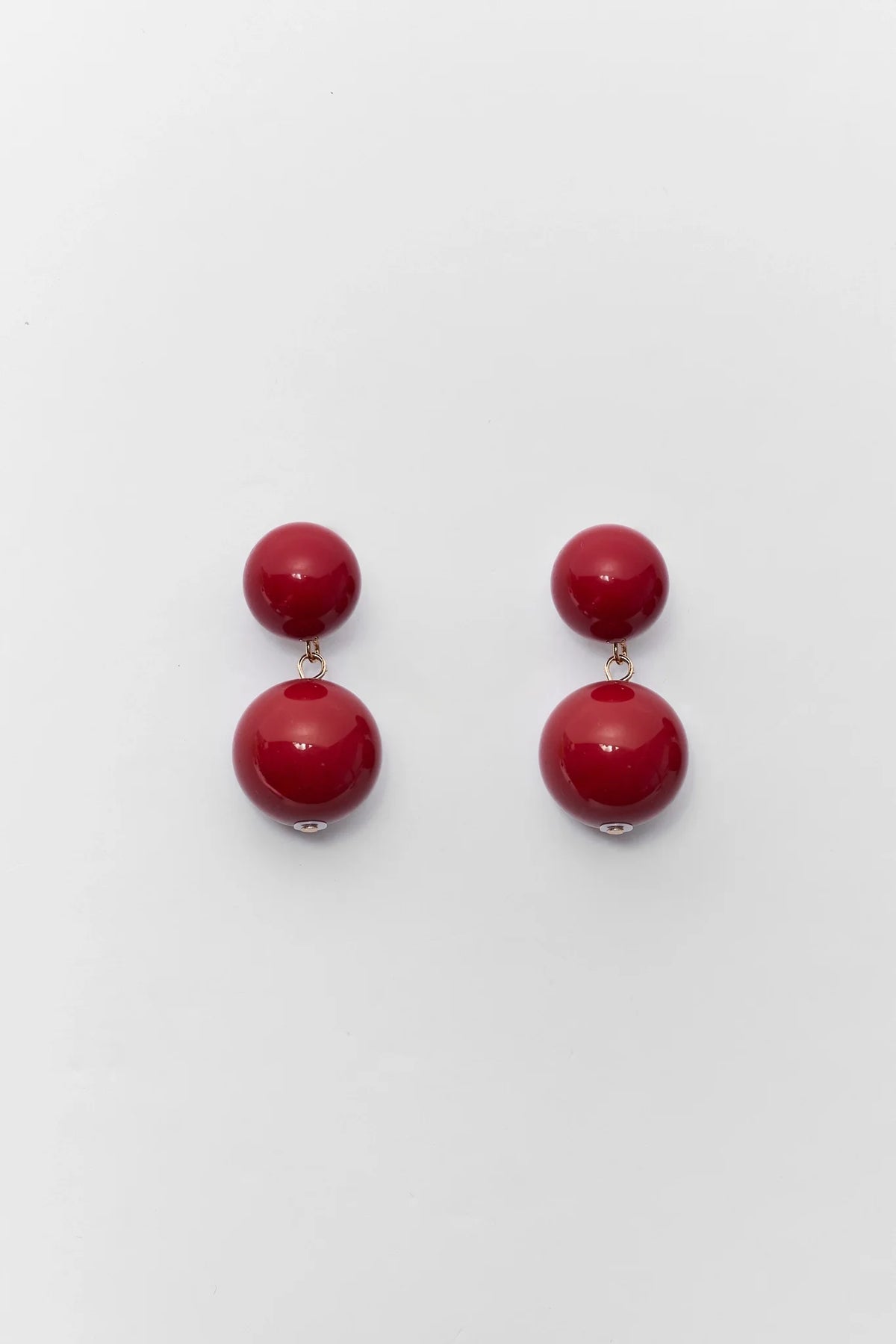 Maroon acrylic drop earrings with double ball design and gold-tone connectors - Flat Lay | Avara