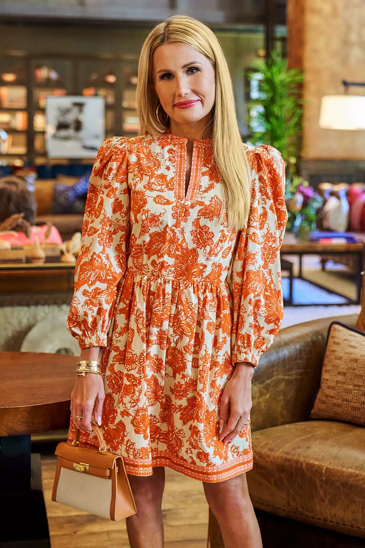 Melanie Orange Floral Short Dress with puff sleeves and keyhole neckline, styled with tan handbag - On Model | Avara