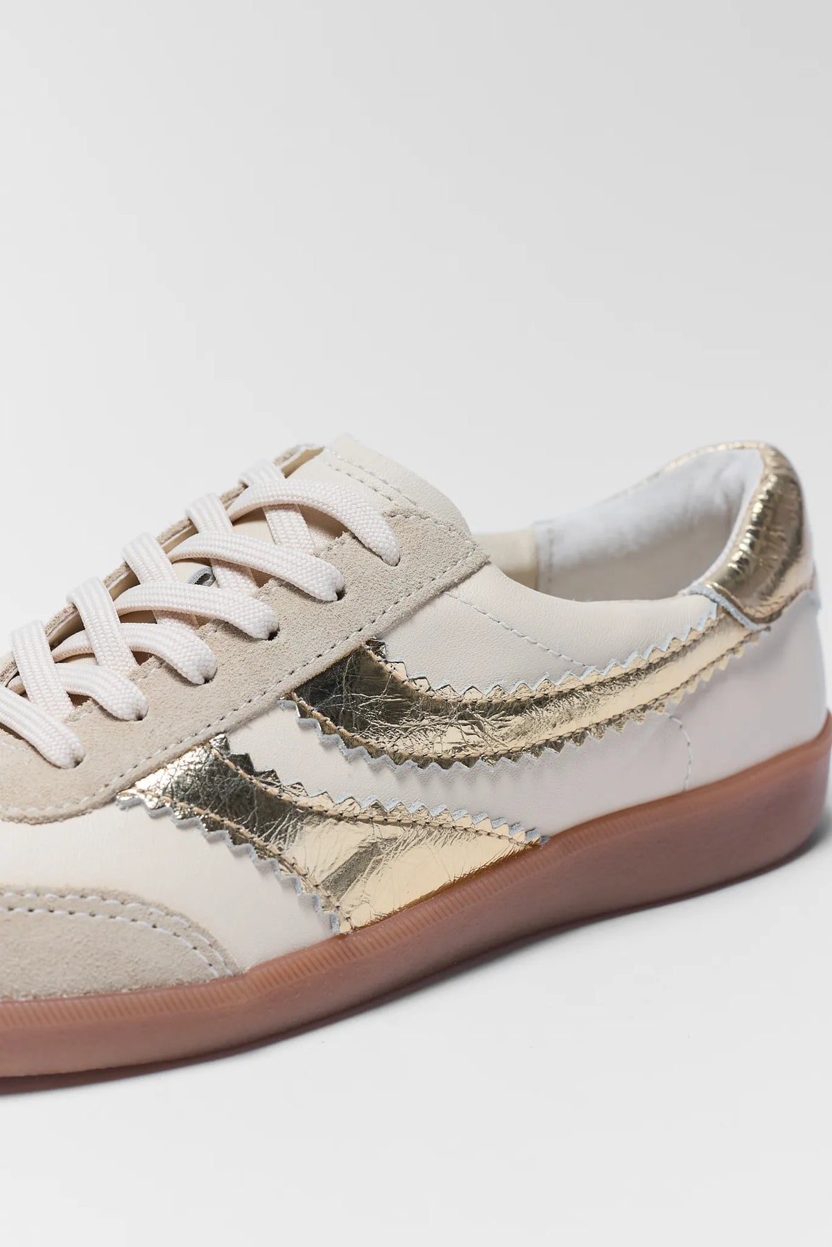 Dolce Vita Merit Gold Sneaker - Close-Up Detail of Metallic Gold Accent Stripe and Gum Sole | Avara