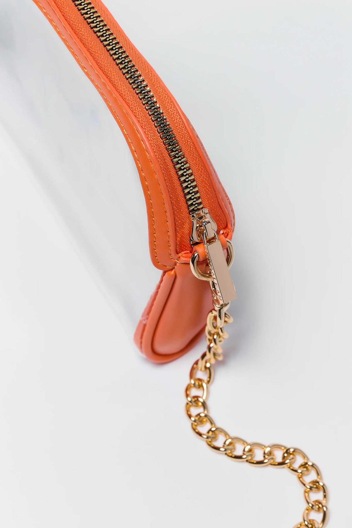 Close-up of orange clear bag zipper and gold-tone chain strap hardware detail — orange clear purse | Avara