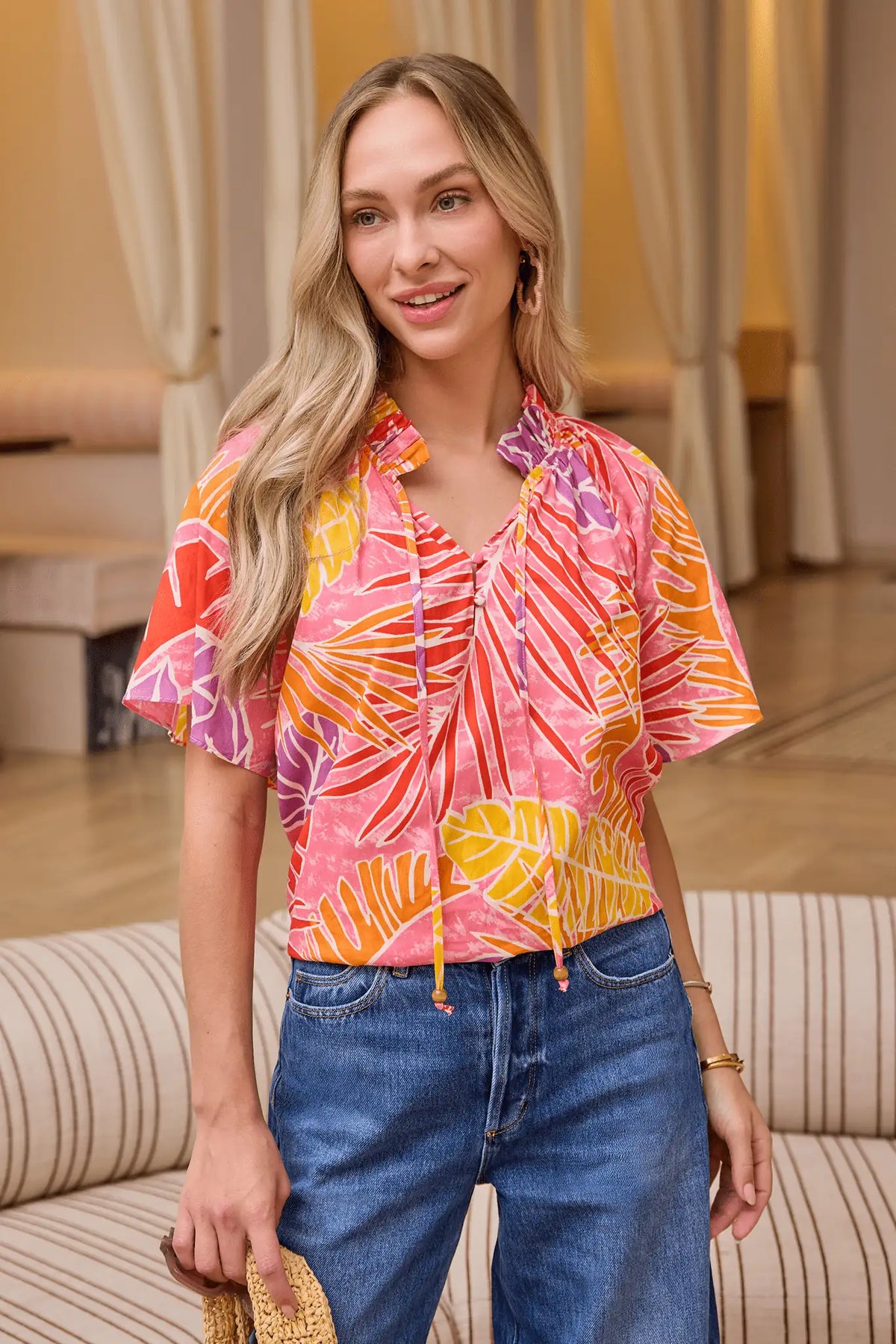 Pink Palm Print Split Neck Top lifestyle shot styled with denim jeans and woven bag, vacation-ready look | Avara