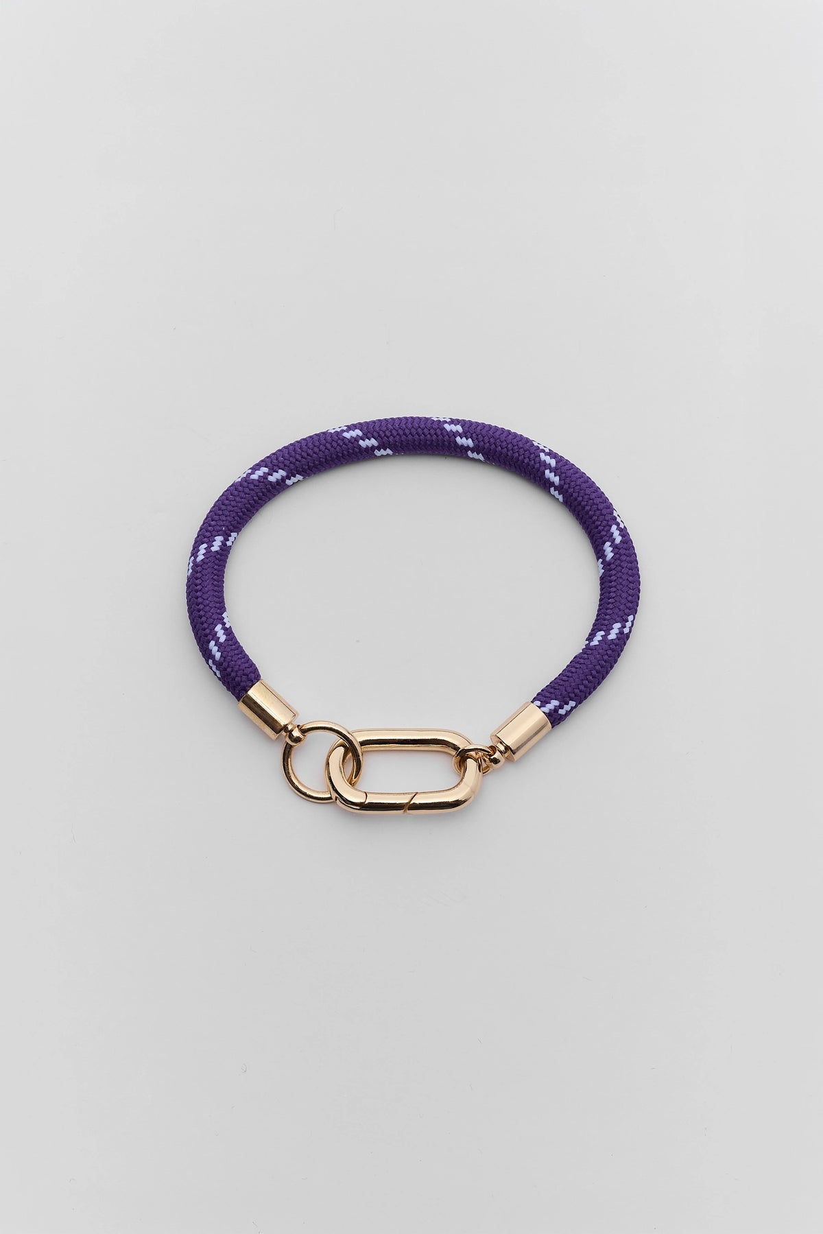 Purple cord carabiner bracelet with gold-tone closure and white accent pattern - Flat Lay | Avara