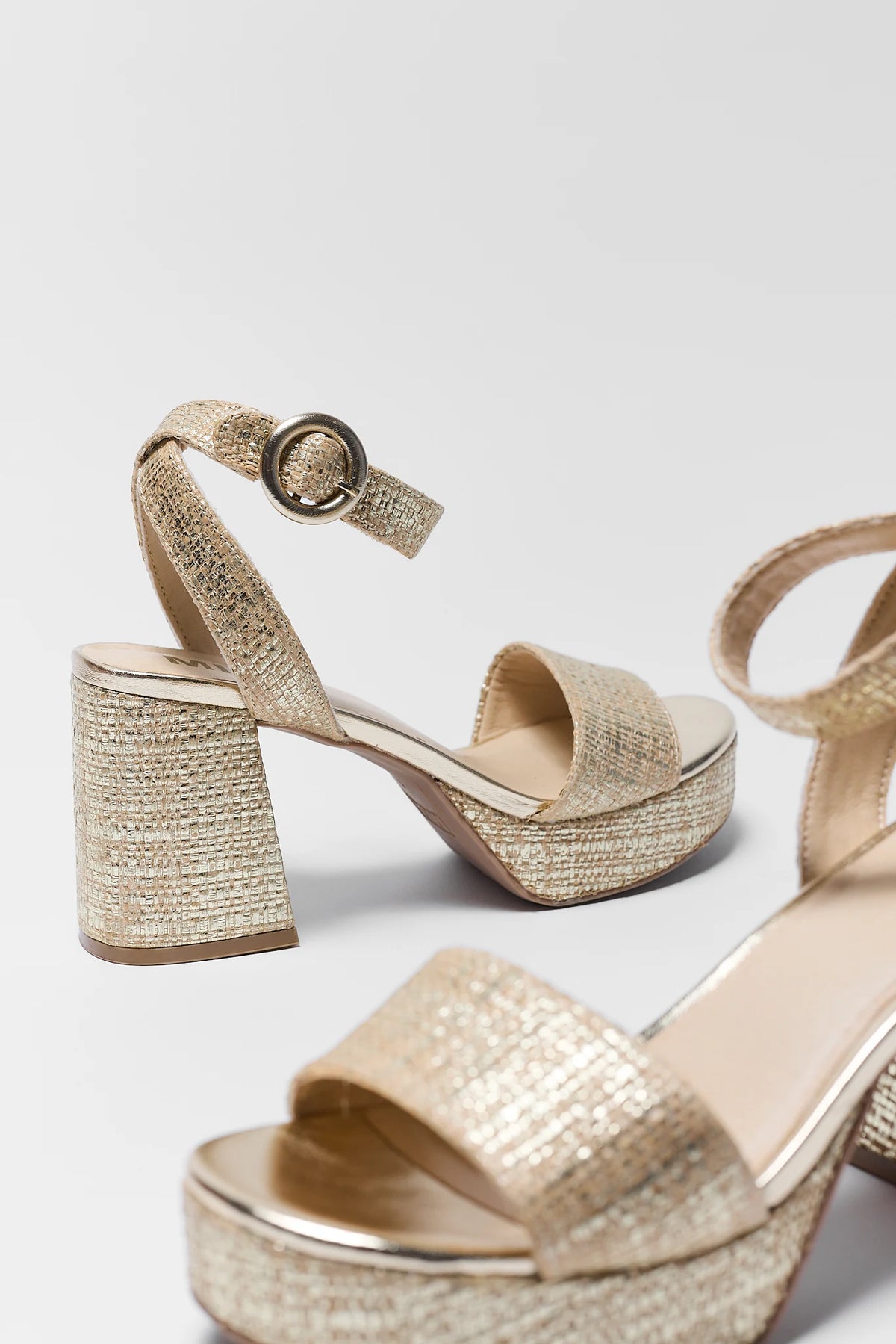 Pair of gold platform sandals with block heel close-up showing woven texture detail | Avara