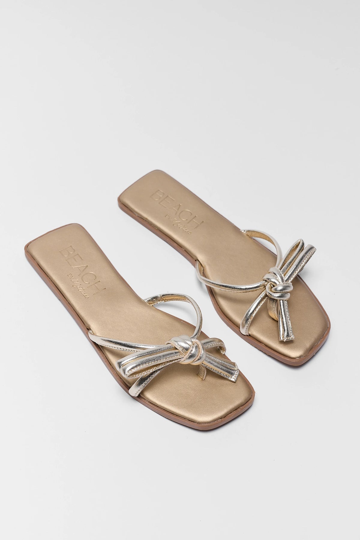 Pair of gold knot sandals overhead flat lay showing bow detail - Ruthie by Matisse | Avara