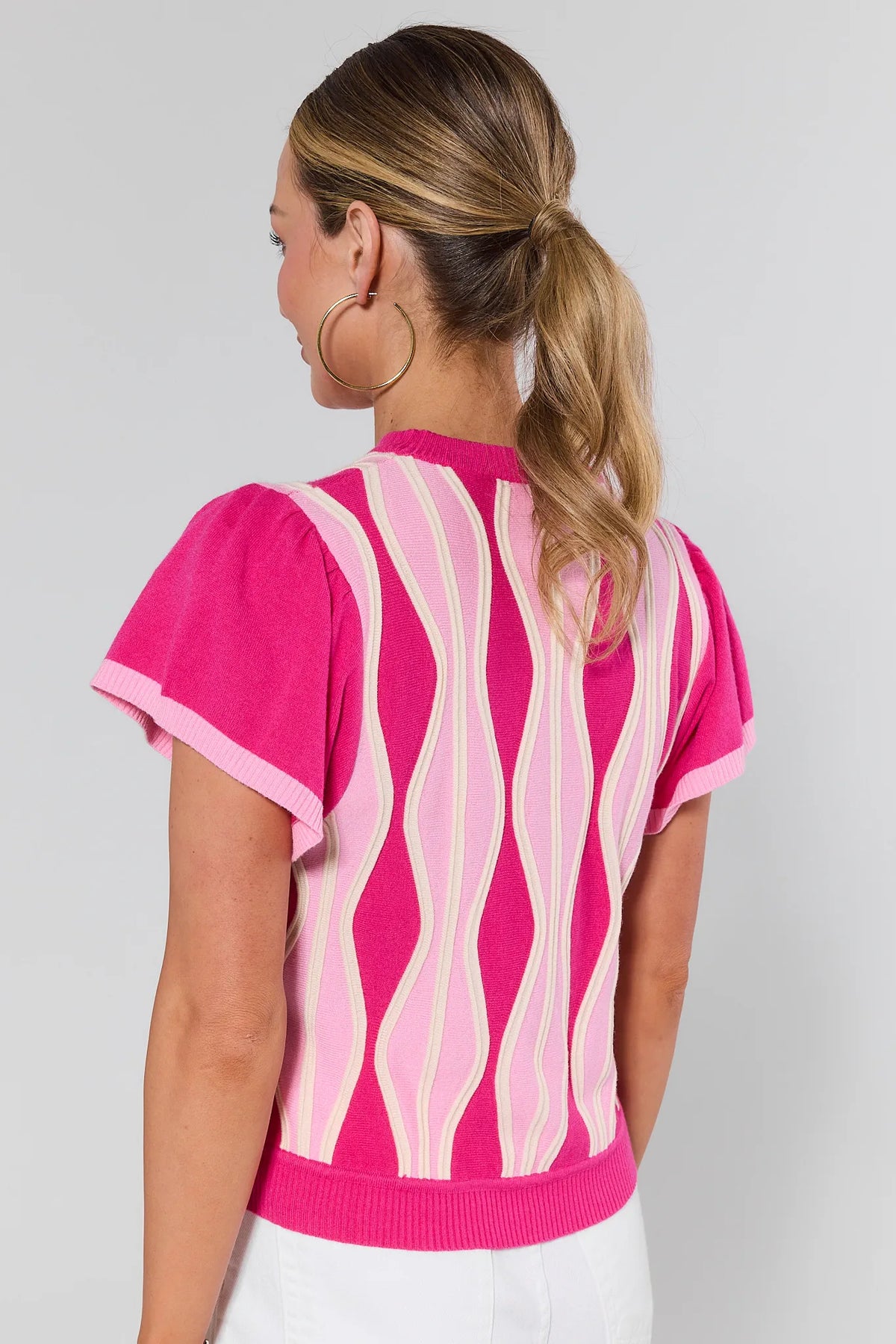 Woman wearing a pink and white patterned top on a plain background