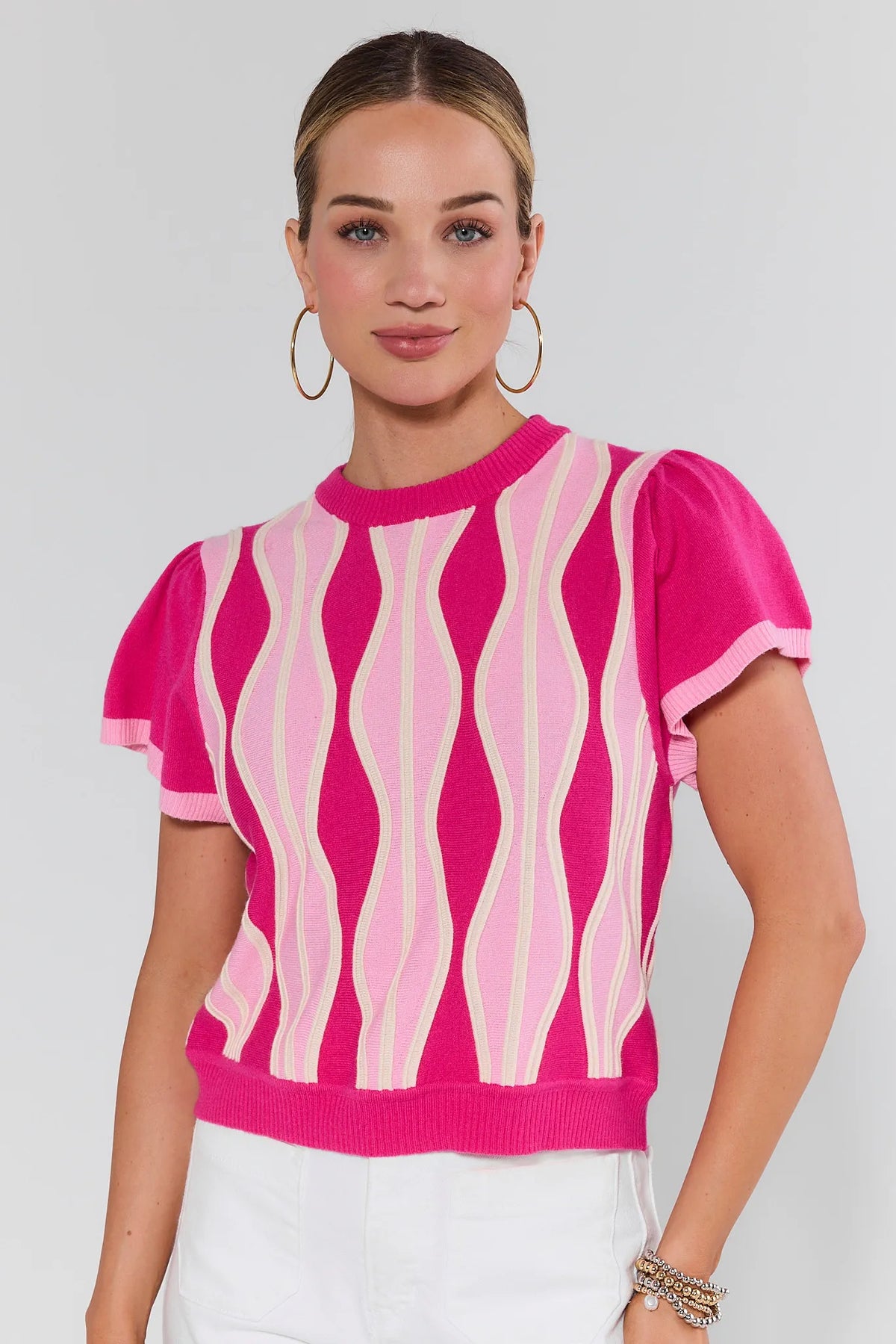 Woman wearing a pink and white patterned top against a plain background