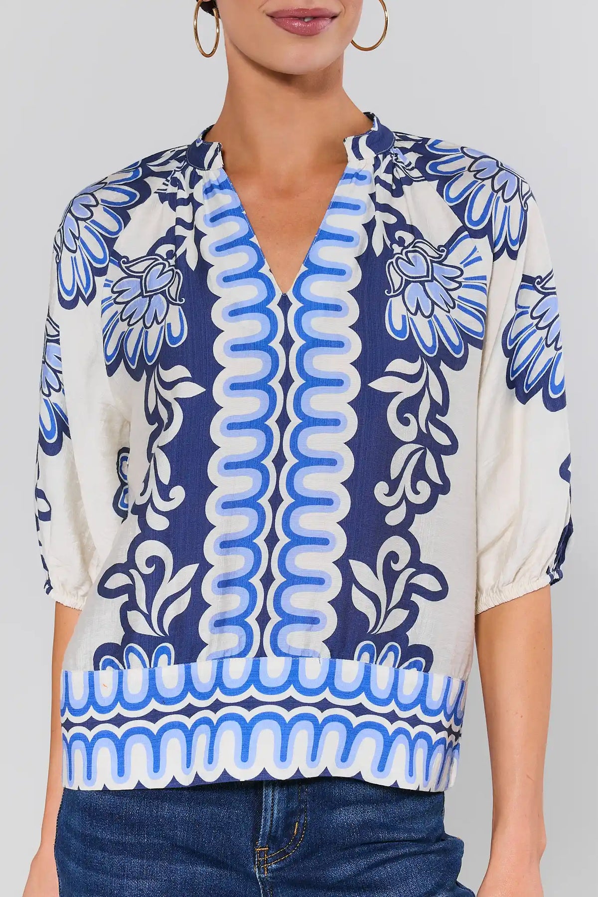close up Woman wearing a blue and white patterned blouse with a plain background