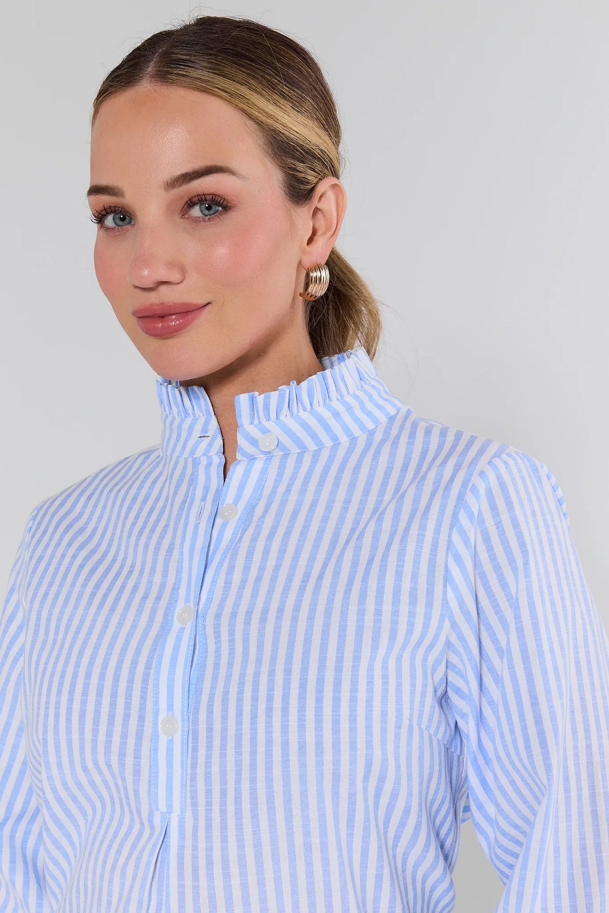 Woman wearing a blue and white striped shirt against a plain background