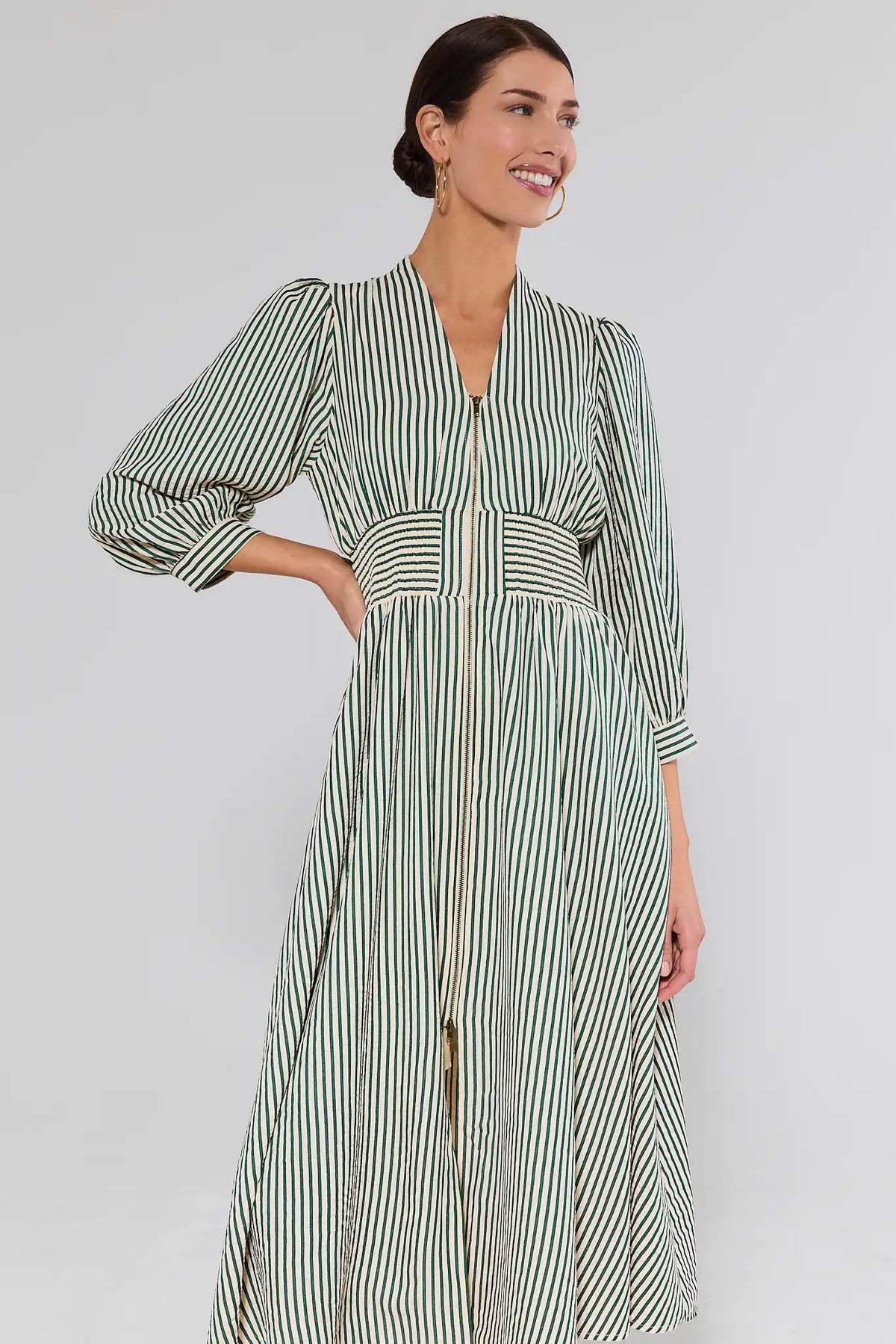 Woman wearing green striped Brantley Midi Dress with smocked waist and zip front - Three-Quarter View | Avara