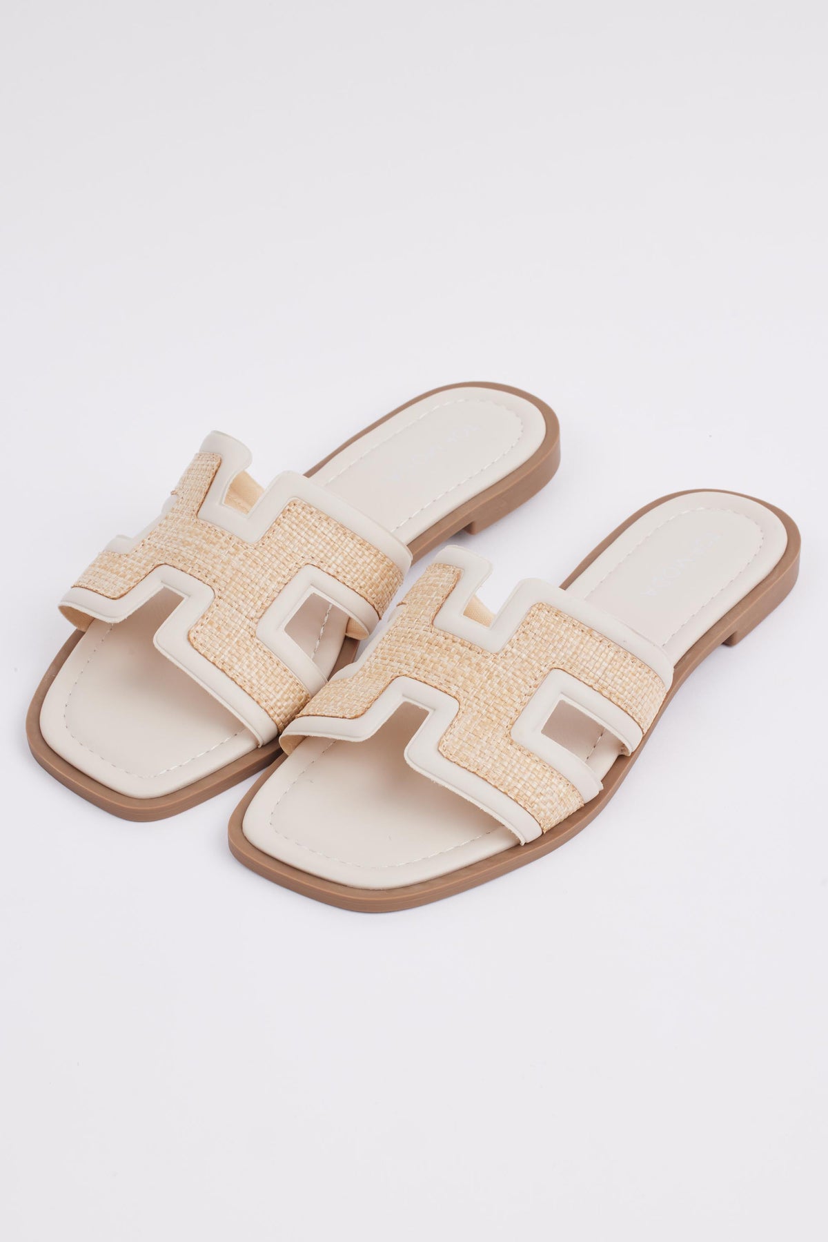 Cream raffia slide sandals pair with woven H-strap and tan rubber sole - Angled View | Avara
