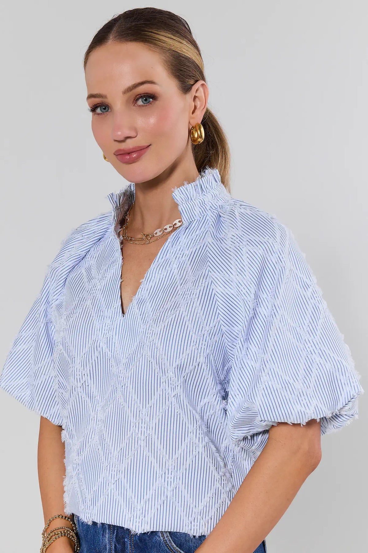 Woman wearing a blue and white striped shirt against a light background