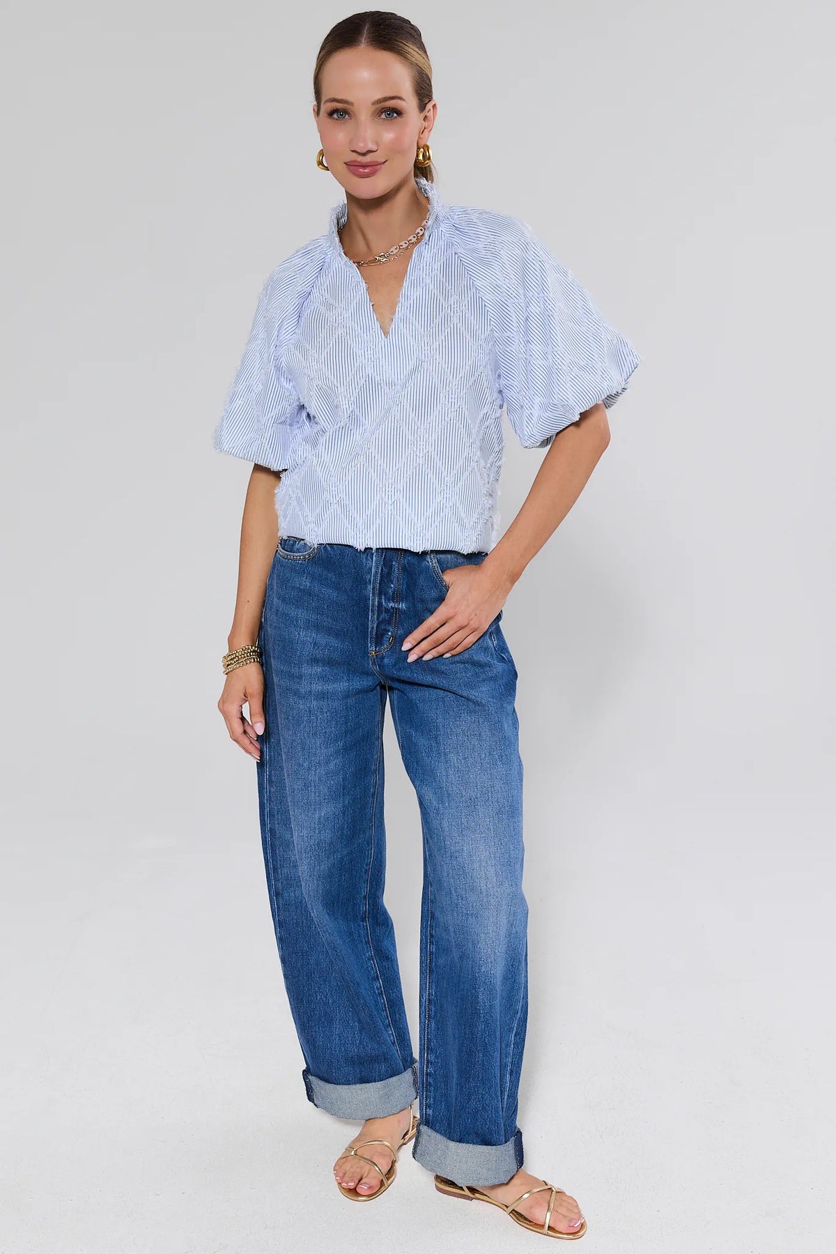 Woman wearing a light patterned shirt and blue jeans on a background