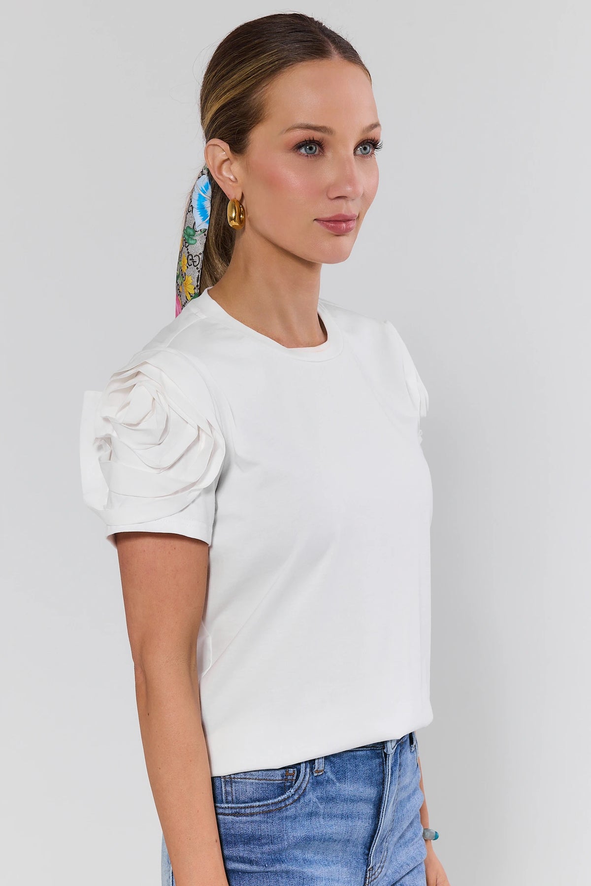 Kendall White Floral Appliqué Top side profile showing rose appliqué sleeve detail, styled with jeans | Avara