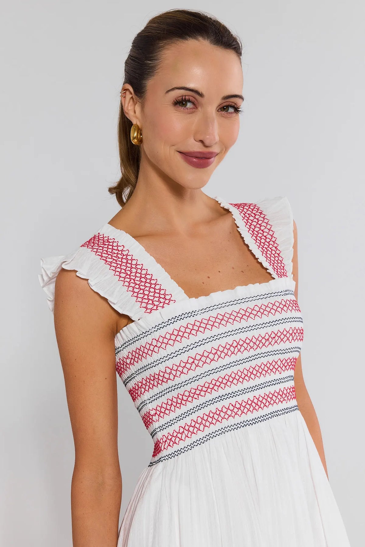 Close-up of white embroidered dress bodice with red and navy contrast stitching and ruffle cap sleeves | Avara