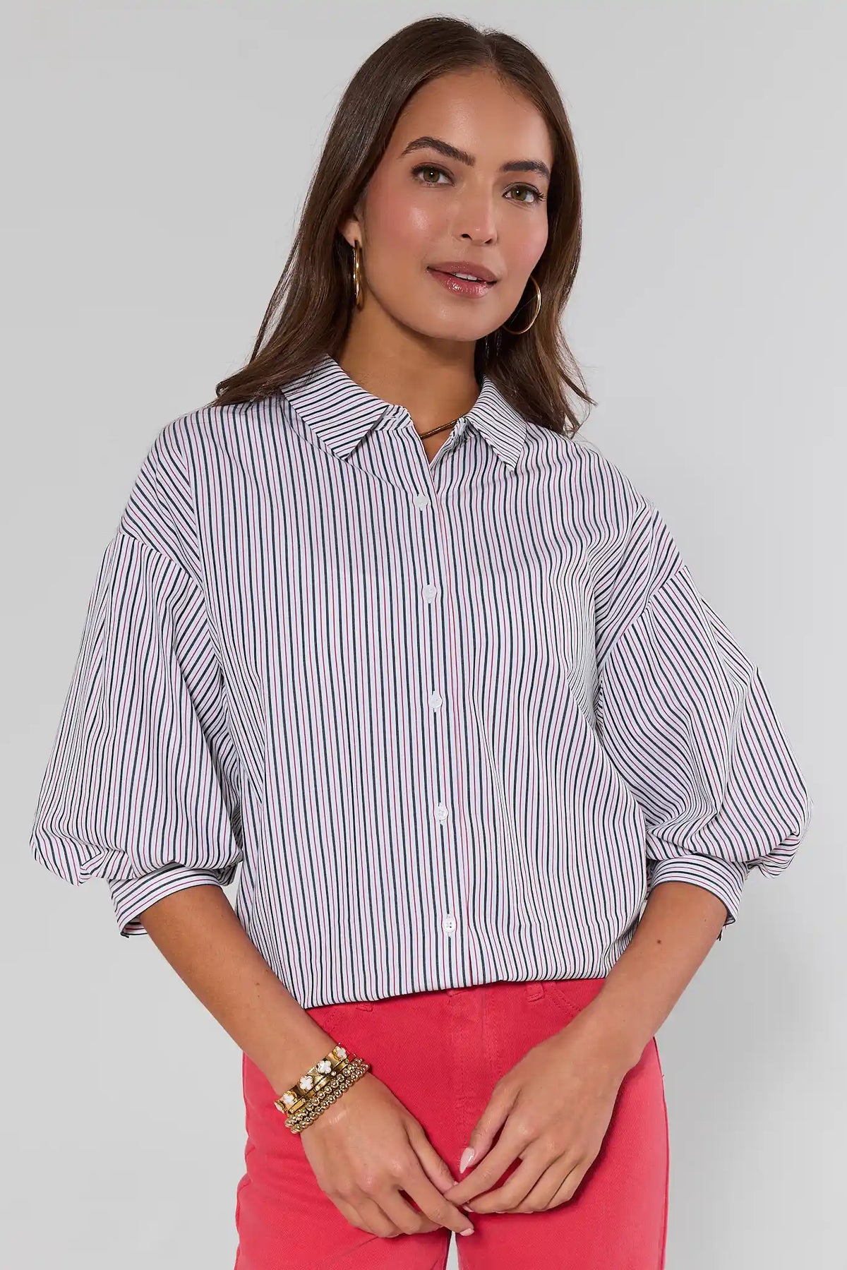 Woman wearing a striped shirt and pink skirt against a plain background