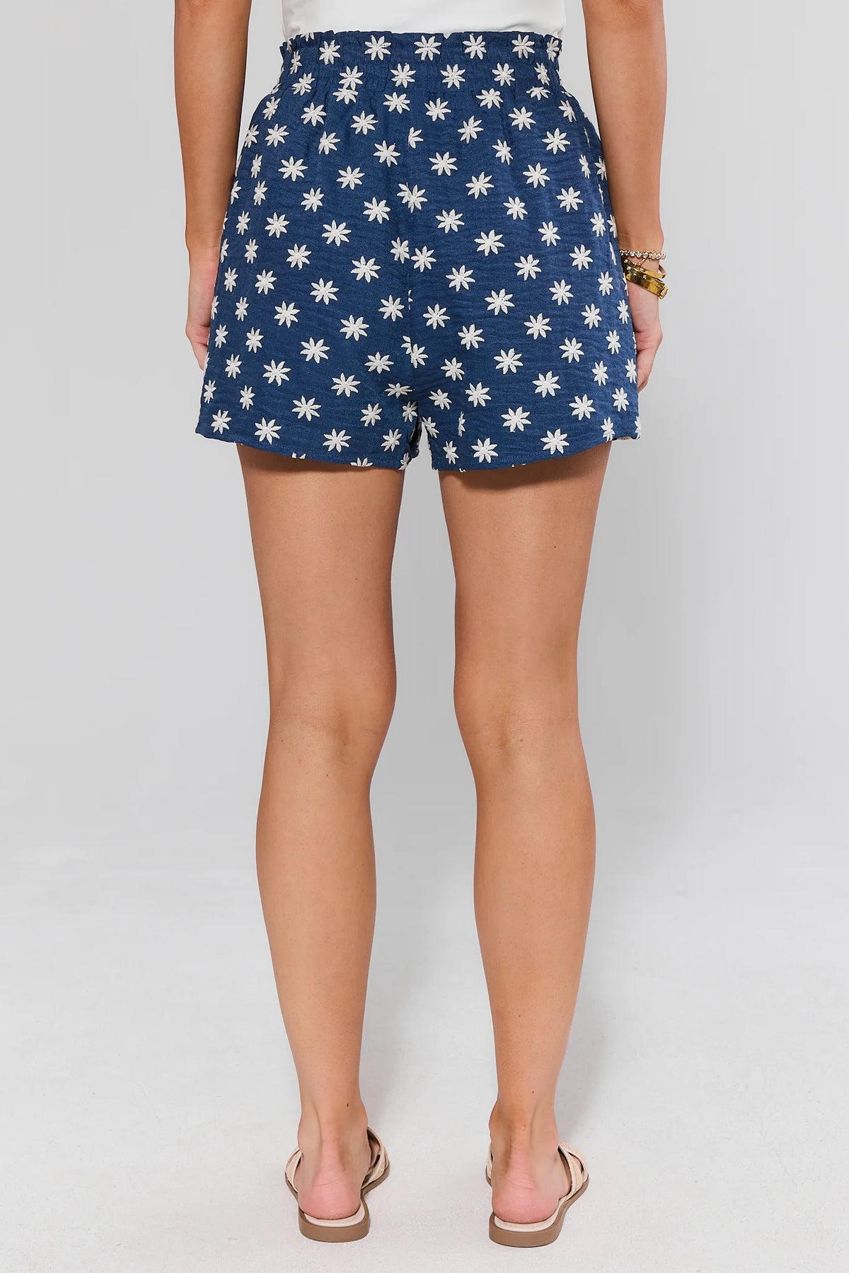 Navy chambray floral embroidered shorts, elastic ruffle waistband back view on model | Avara