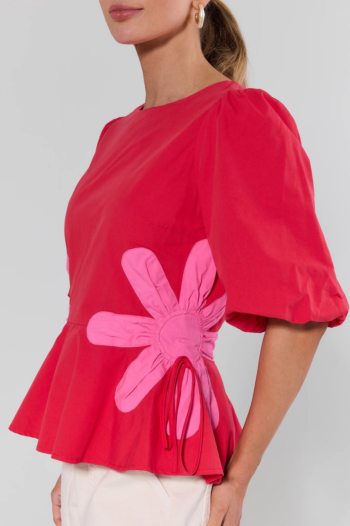 Red blouse with a pink flower design on a plain background