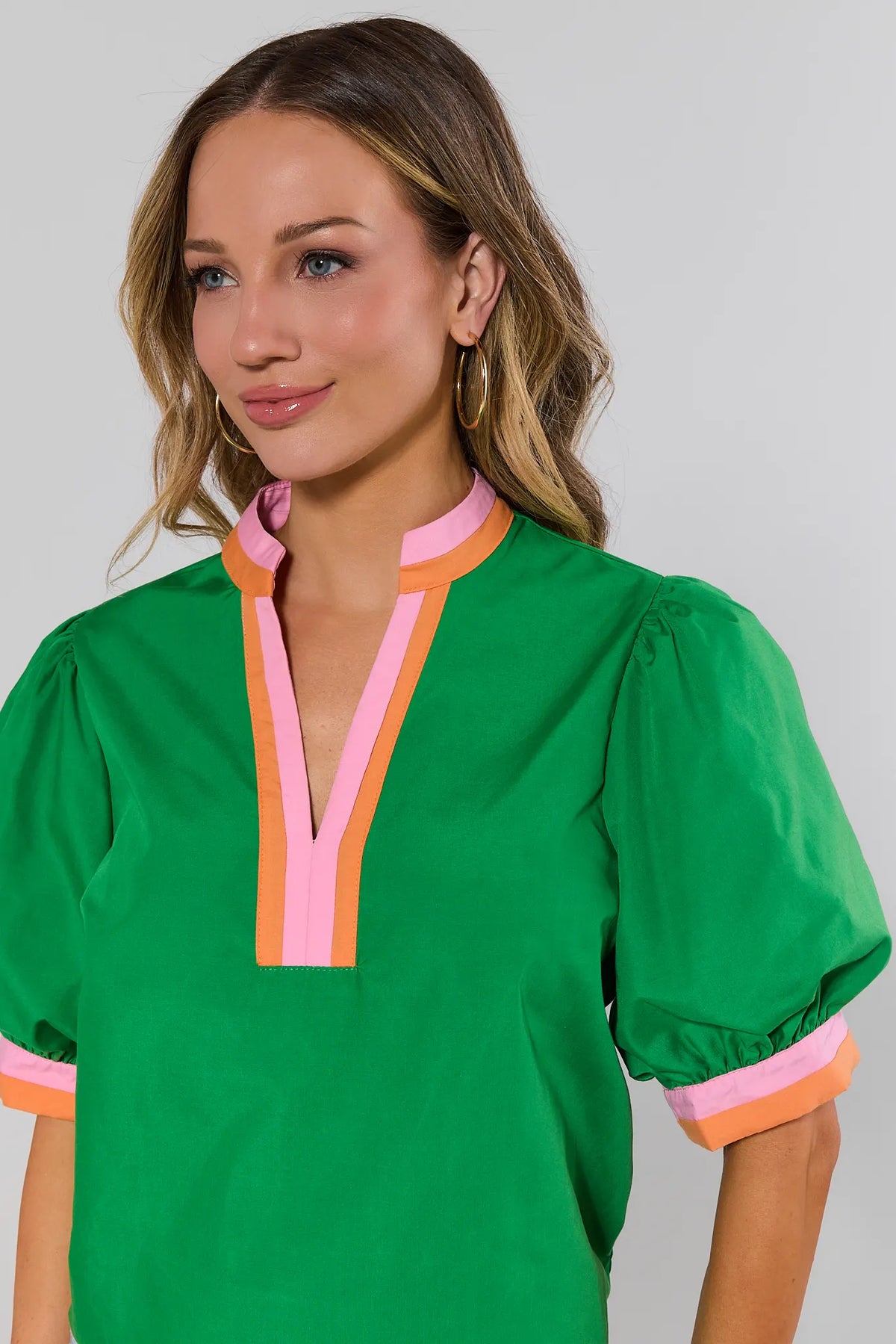 close up Woman wearing a green blouse with colorful trim on a plain background